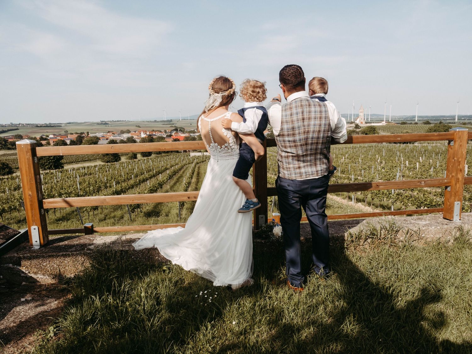 Wedding couple with two children overlooking vineyard countryside on sunny day.