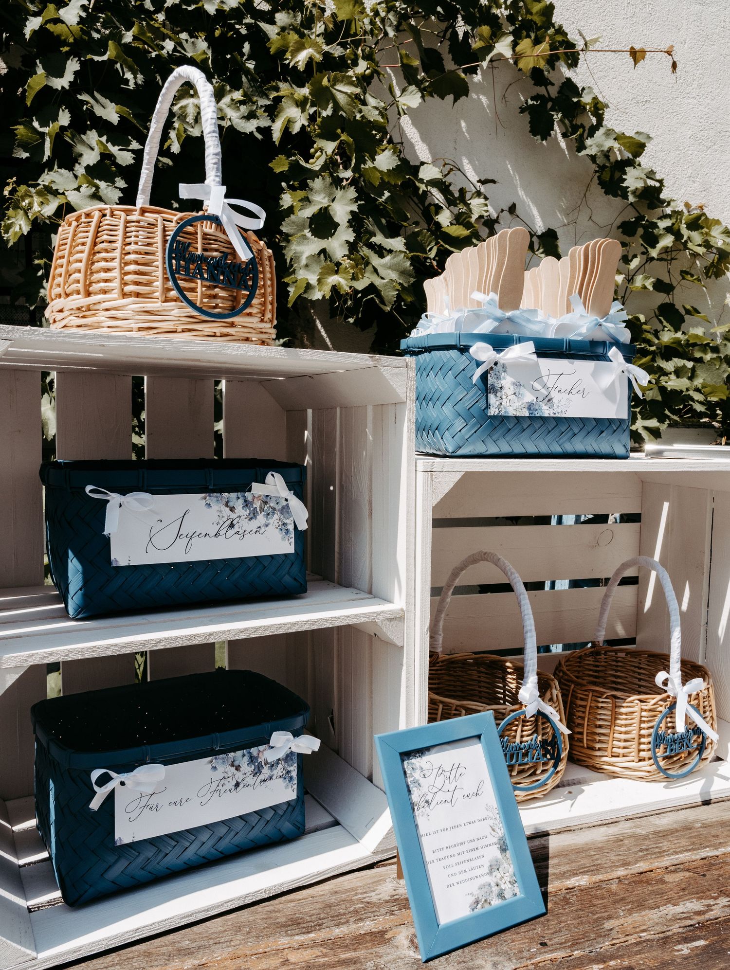 Navy blue velvet boxes and wicker baskets displayed on white wooden crates for an elegant wedding gift table.