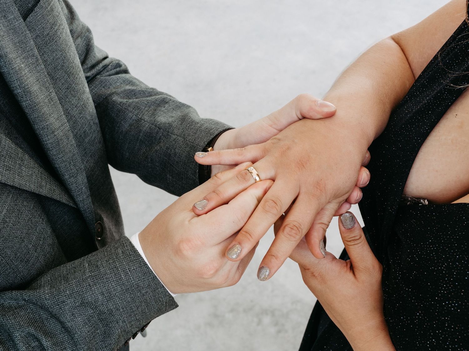 Close-up of a couple exchanging a gold wedding ring during an engagement or wedding ceremony.