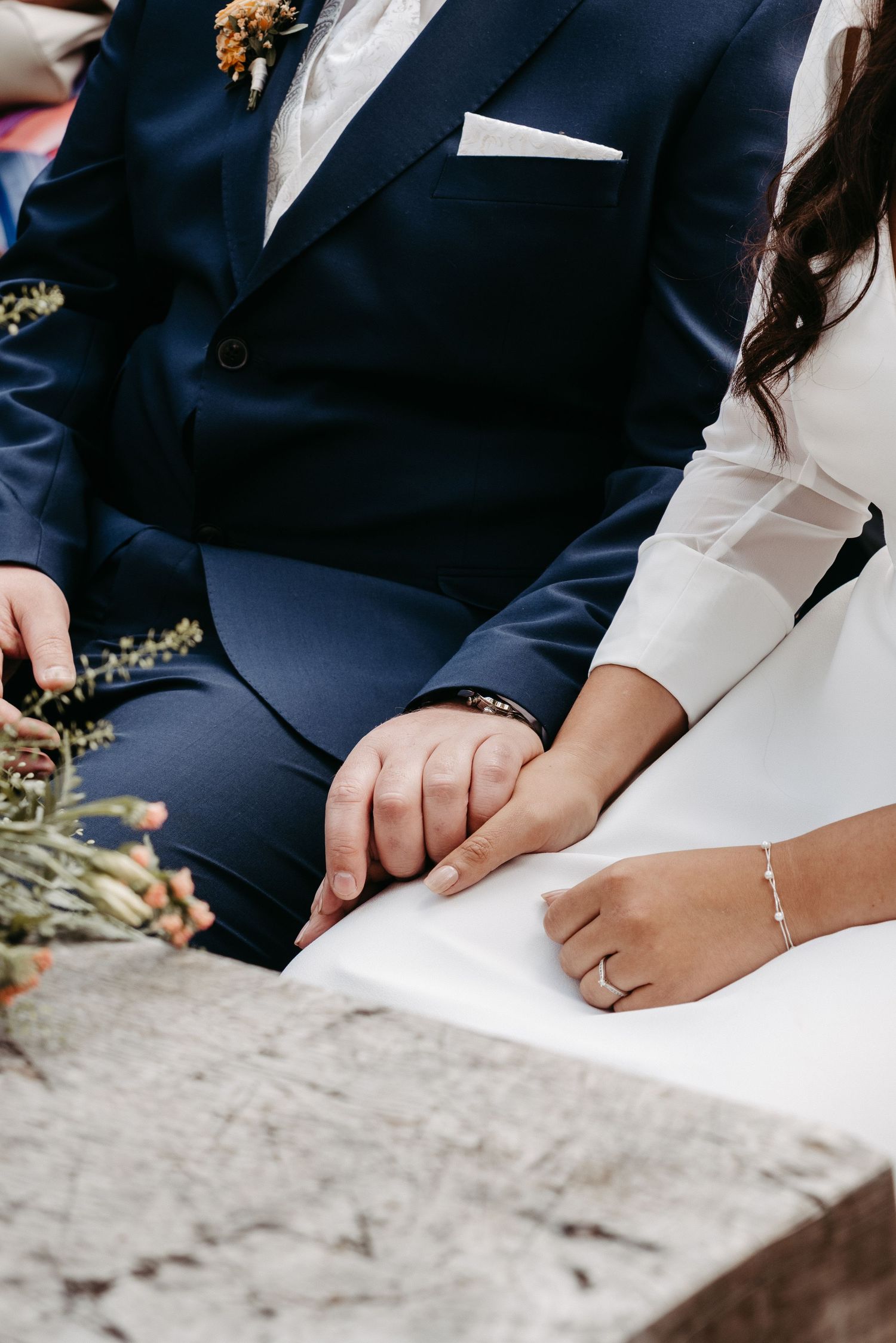 Bride and groom holding hands during wedding ceremony, bride wearing diamond ring.