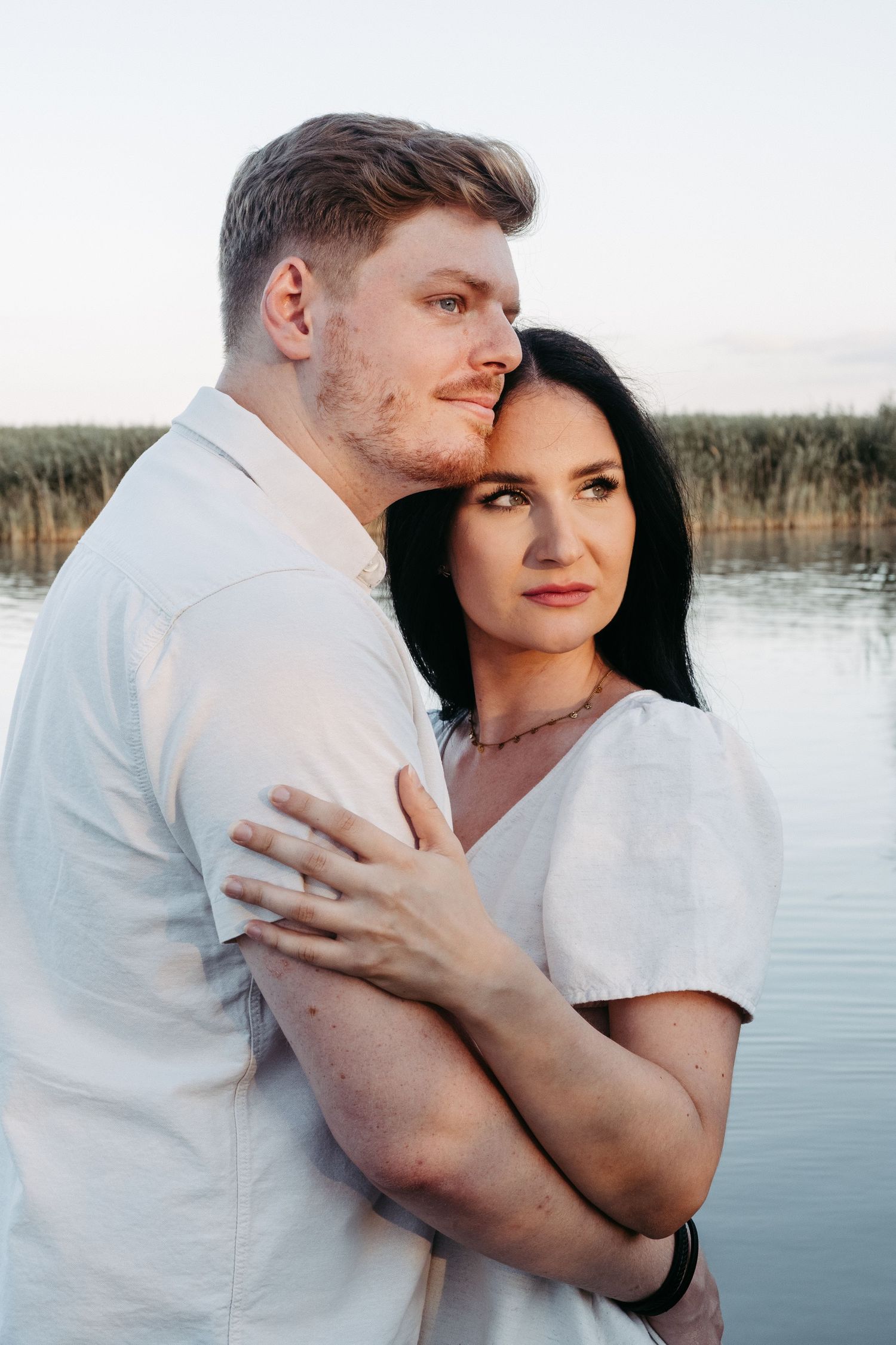 Romantic lakeside couples photos in white outfits at sunset.