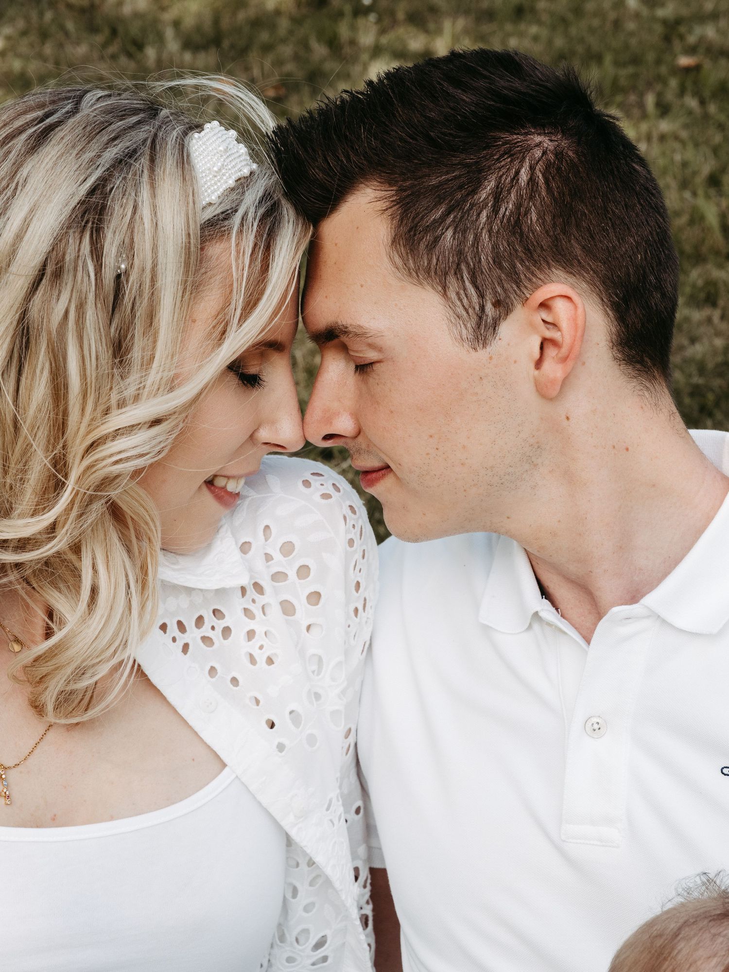 Intimate outdoor portrait shoot featuring a couple in white outfits sharing romantic close-up moments together.