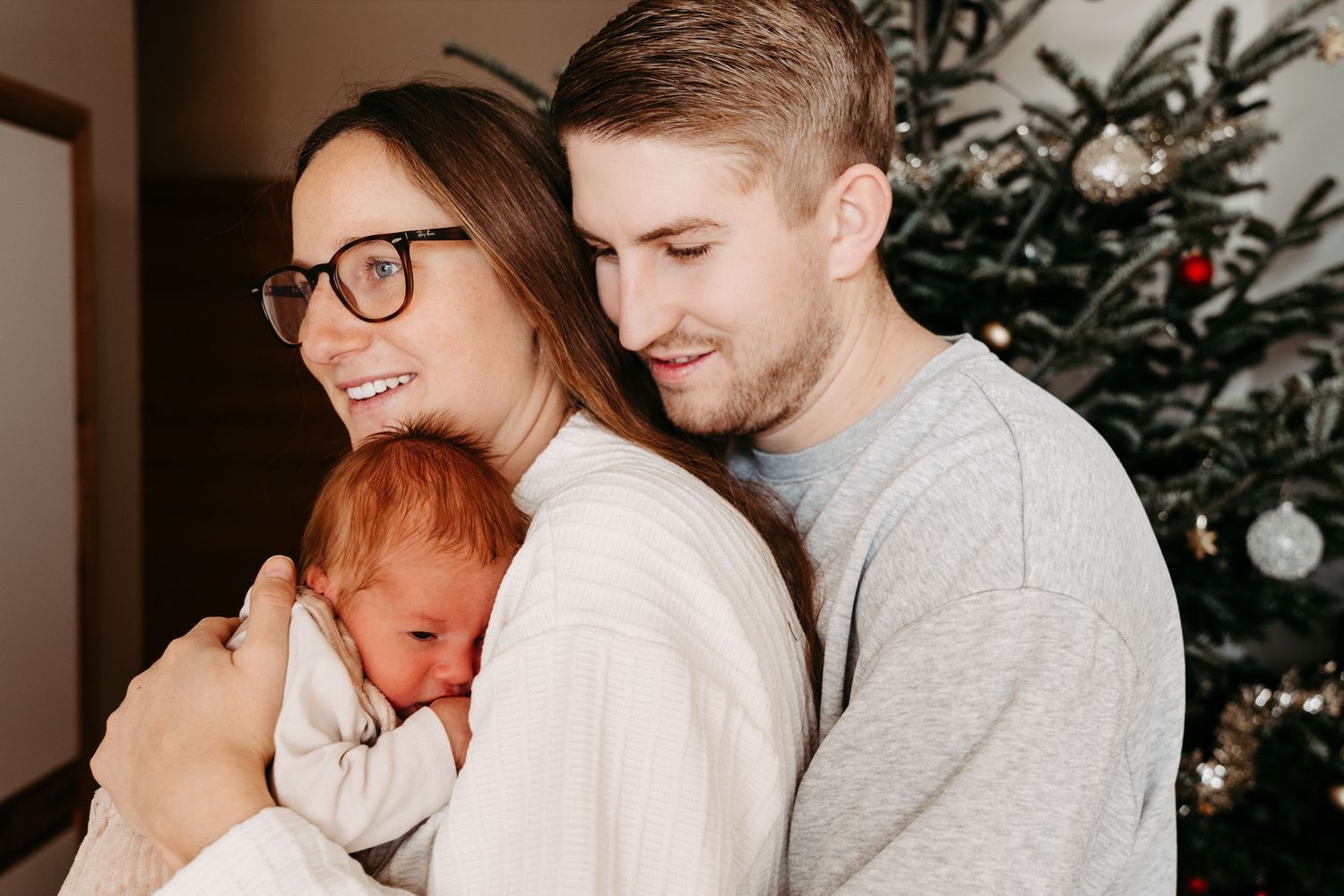 A couple shares tender moments in front of a Christmas tree in a series of intimate holiday photos.