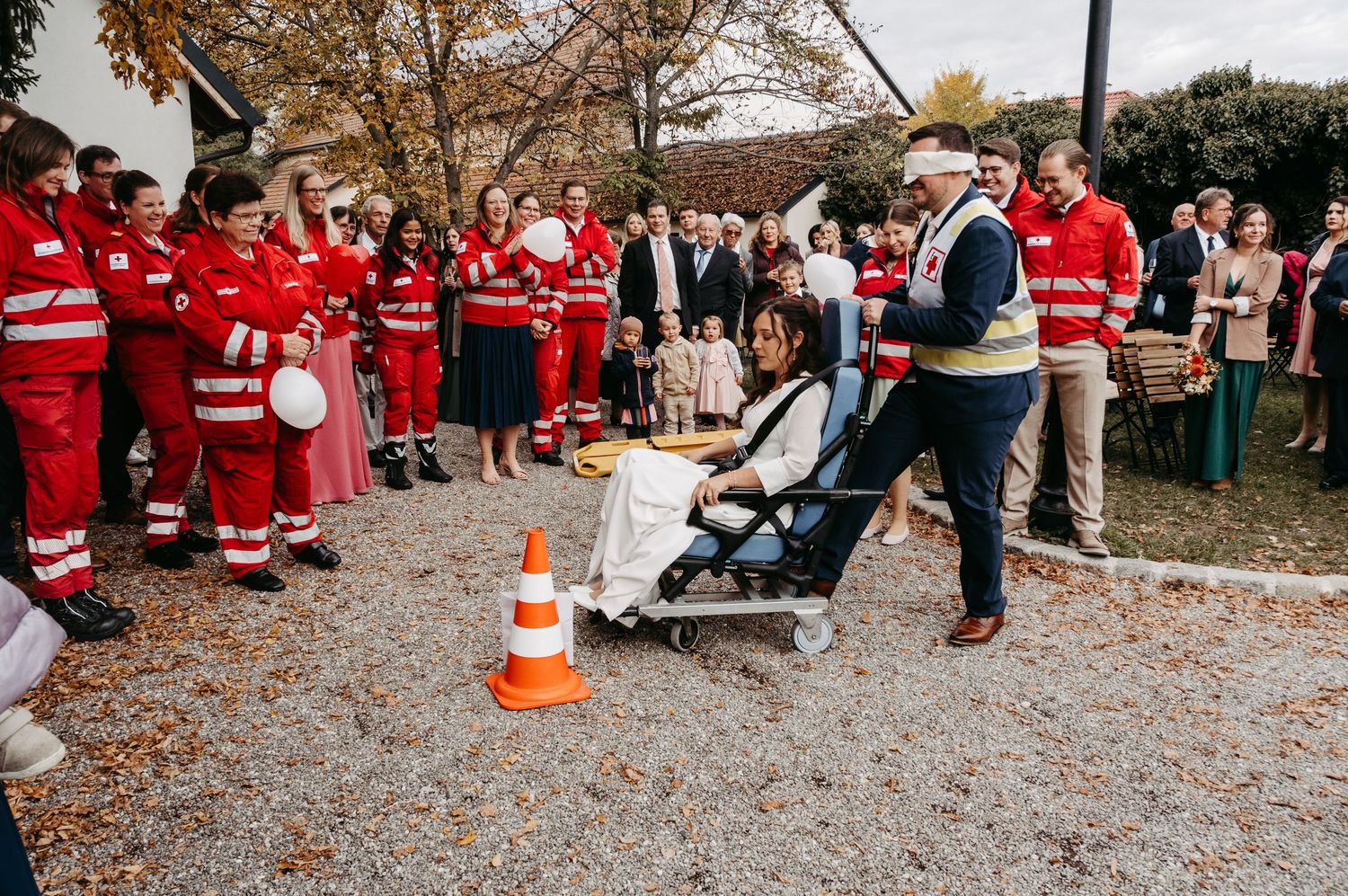 Wedding guests in Red Cross uniforms participate in a fun outdoor game with the bride at a reception.