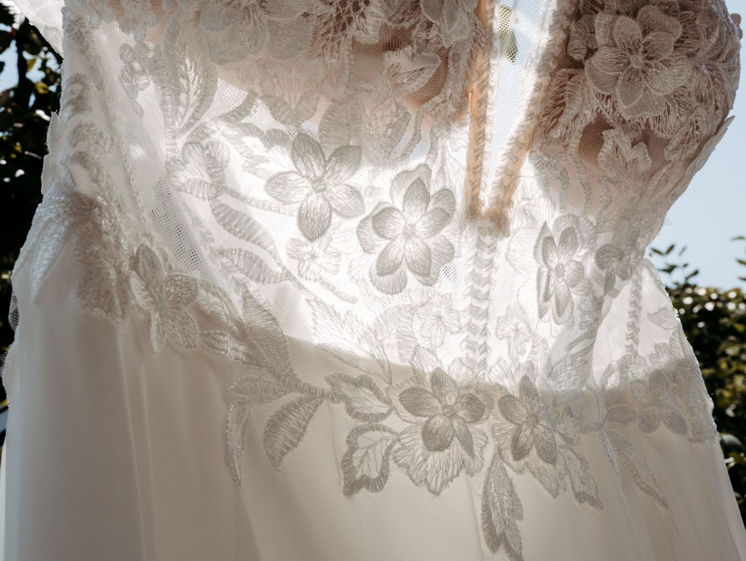 Close-up detail of intricate lace pattern on white wedding dress.