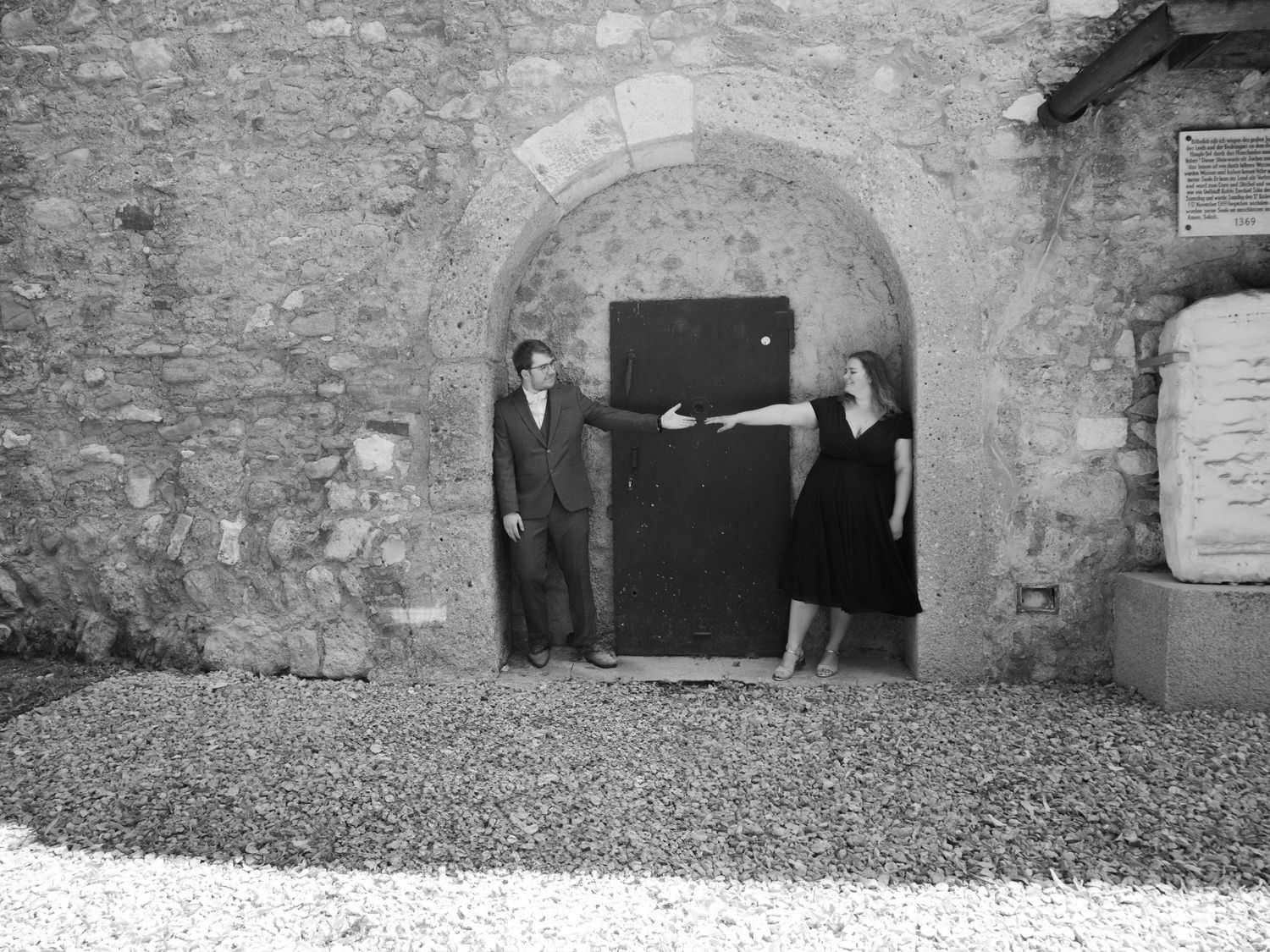 Black and white photo of a man and woman standing in a stone archway doorway at a historic building.
