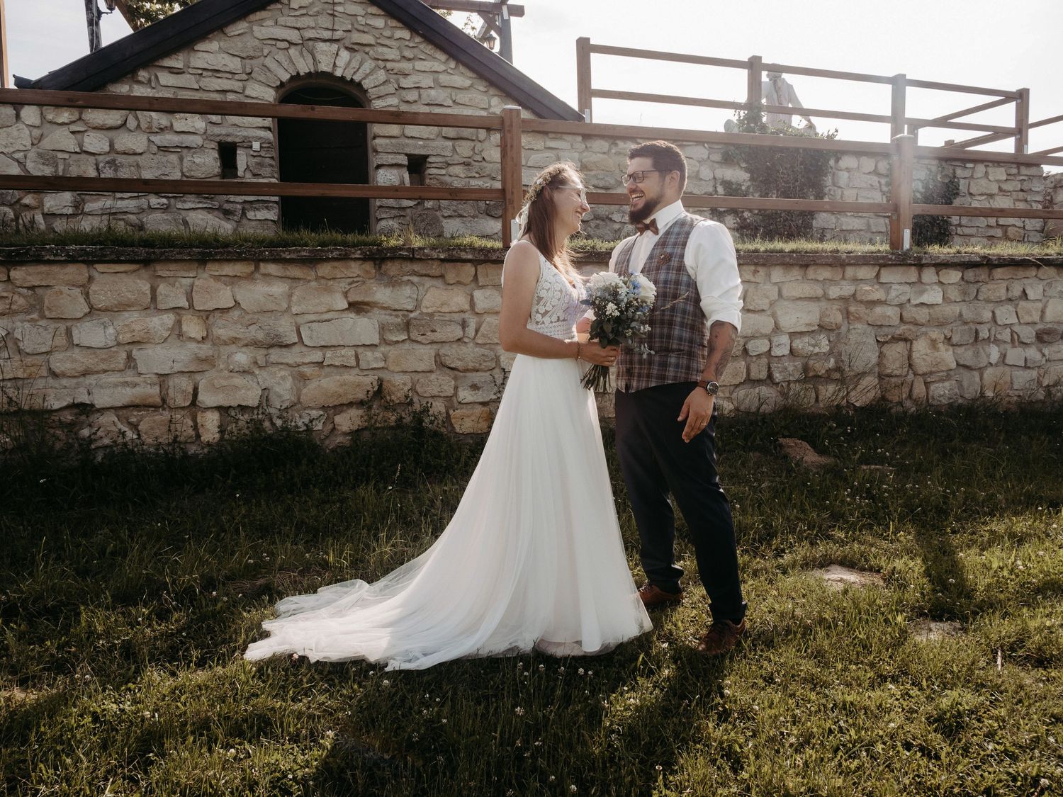 A rustic wedding photoshoot near stone walls and wooden fencing.