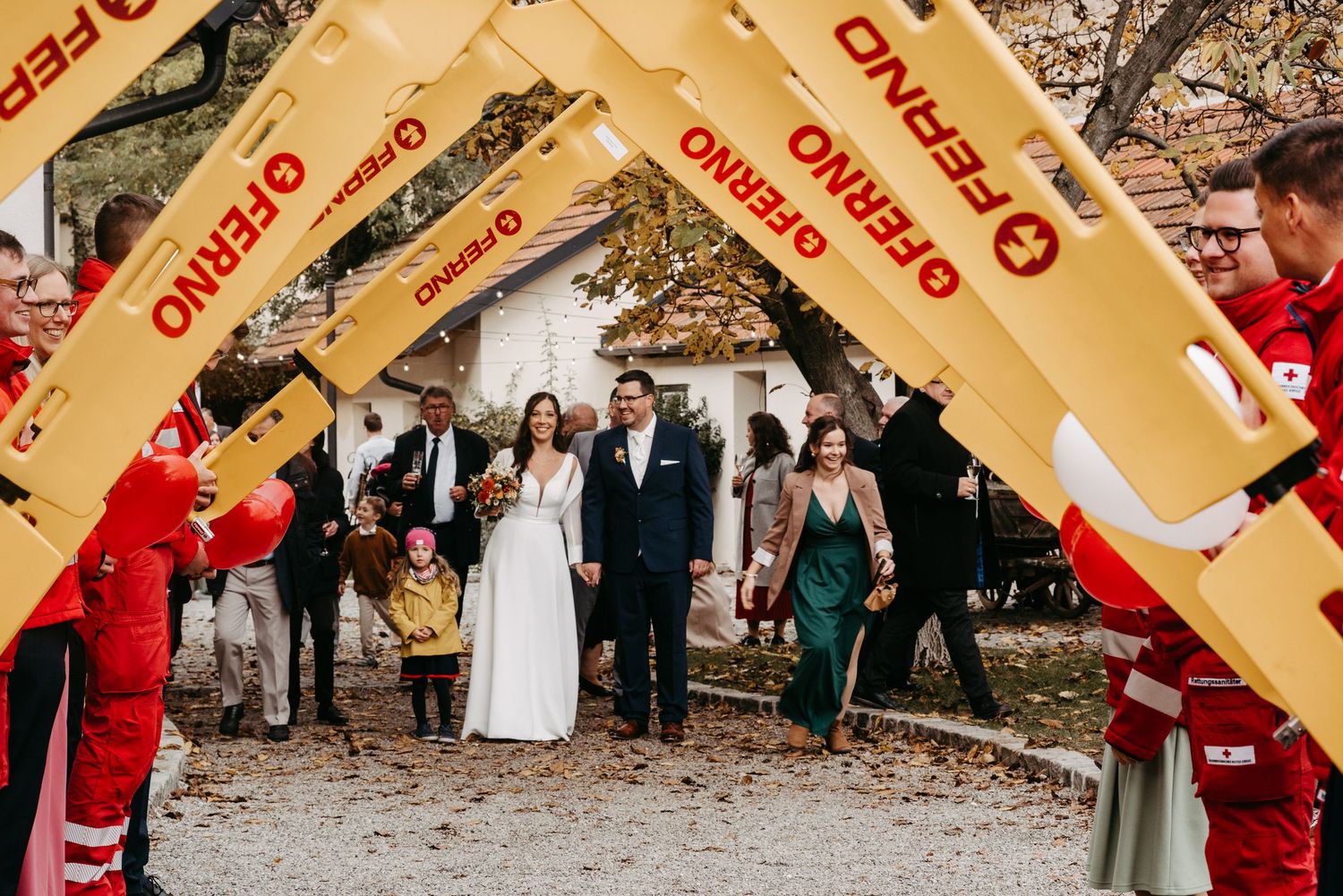 Bride and groom walking through arch of yellow stretchers held by Red Cross volunteers.