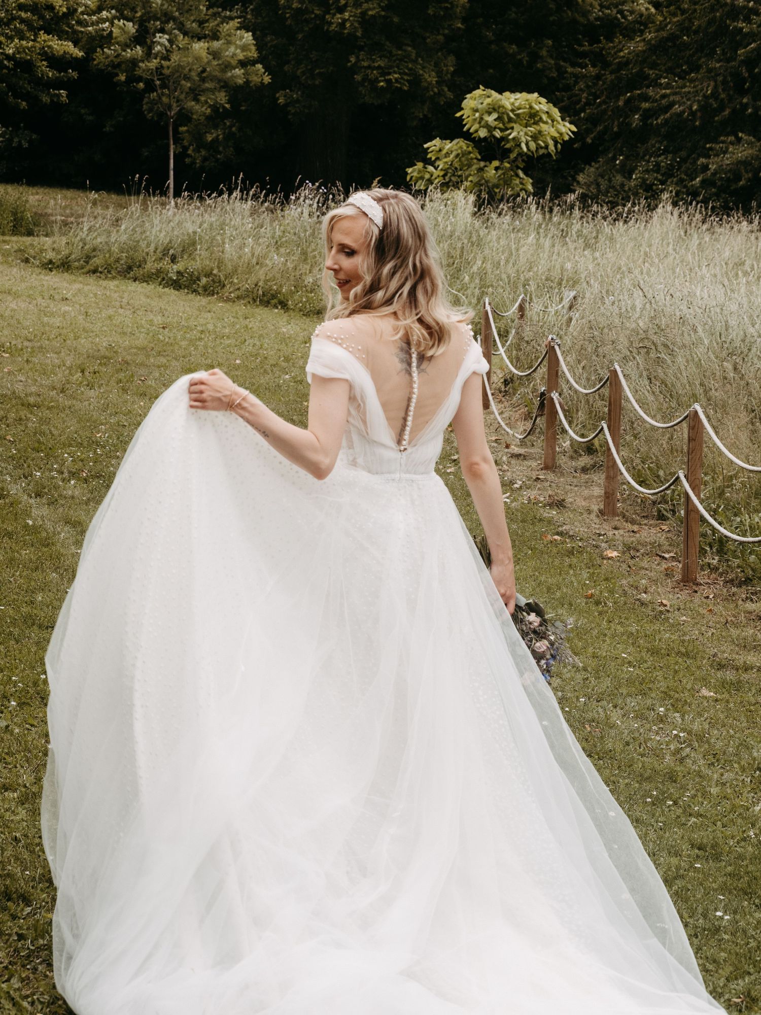 A flowing white wedding dress twirls gracefully in an outdoor garden setting.