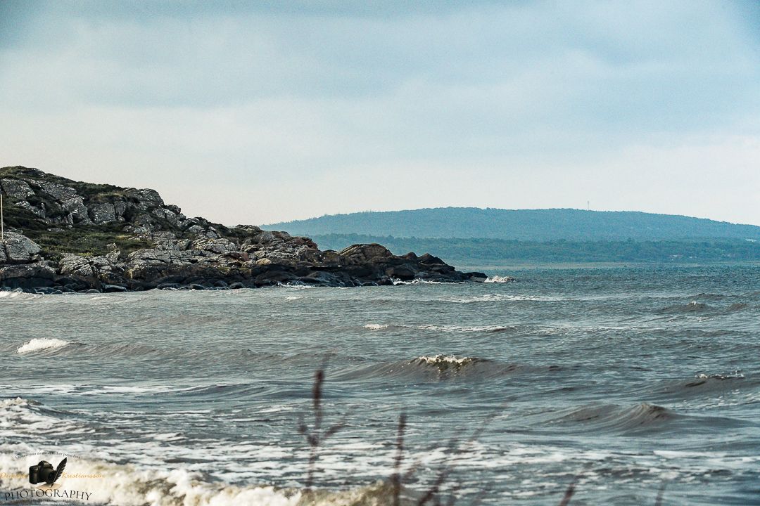 Aerial view of the rugged coastline where waves crash against rocky cliffs along a scenic coastal highway.
