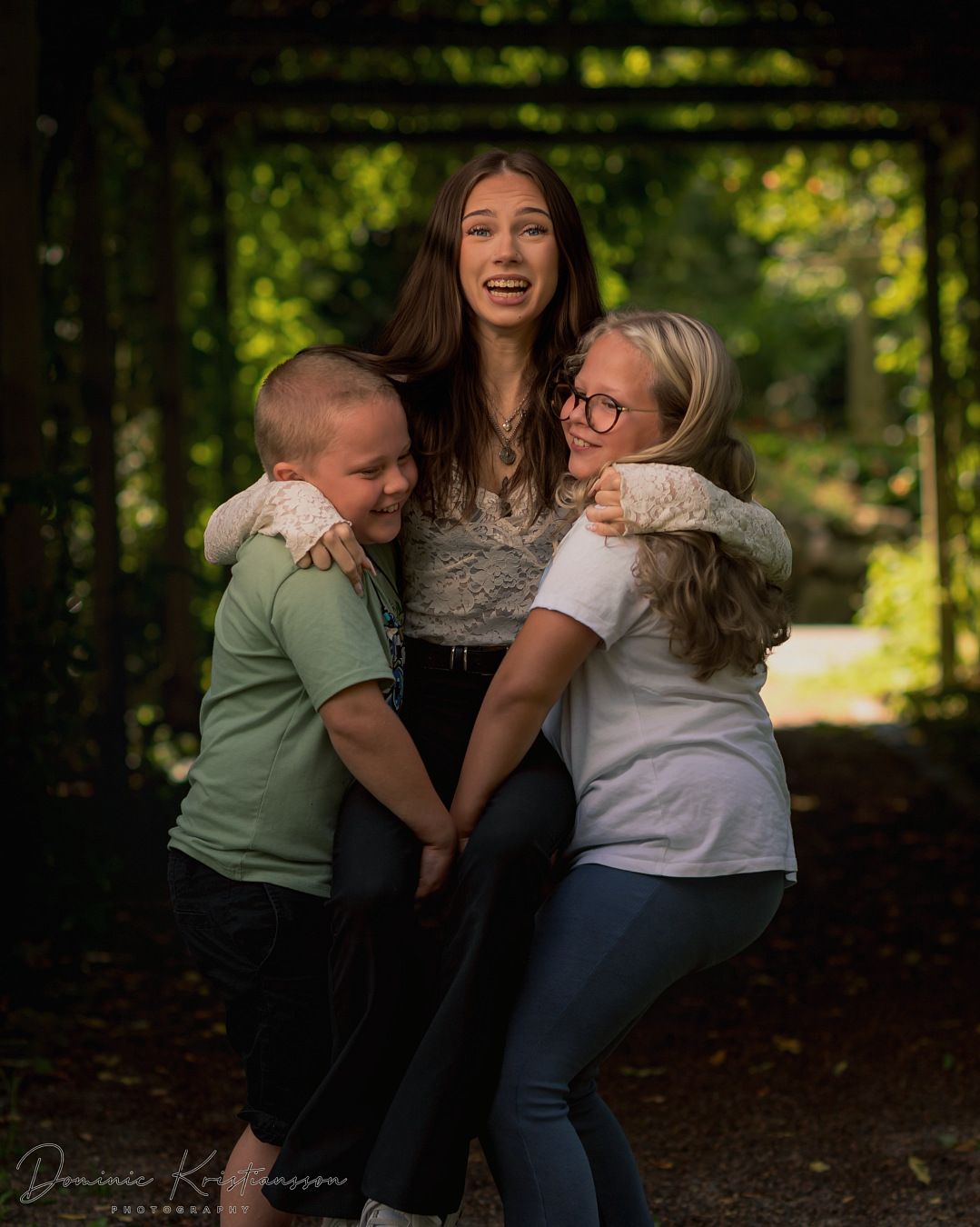 A joyful group hug captured in a wooded setting with natural light filtering through.