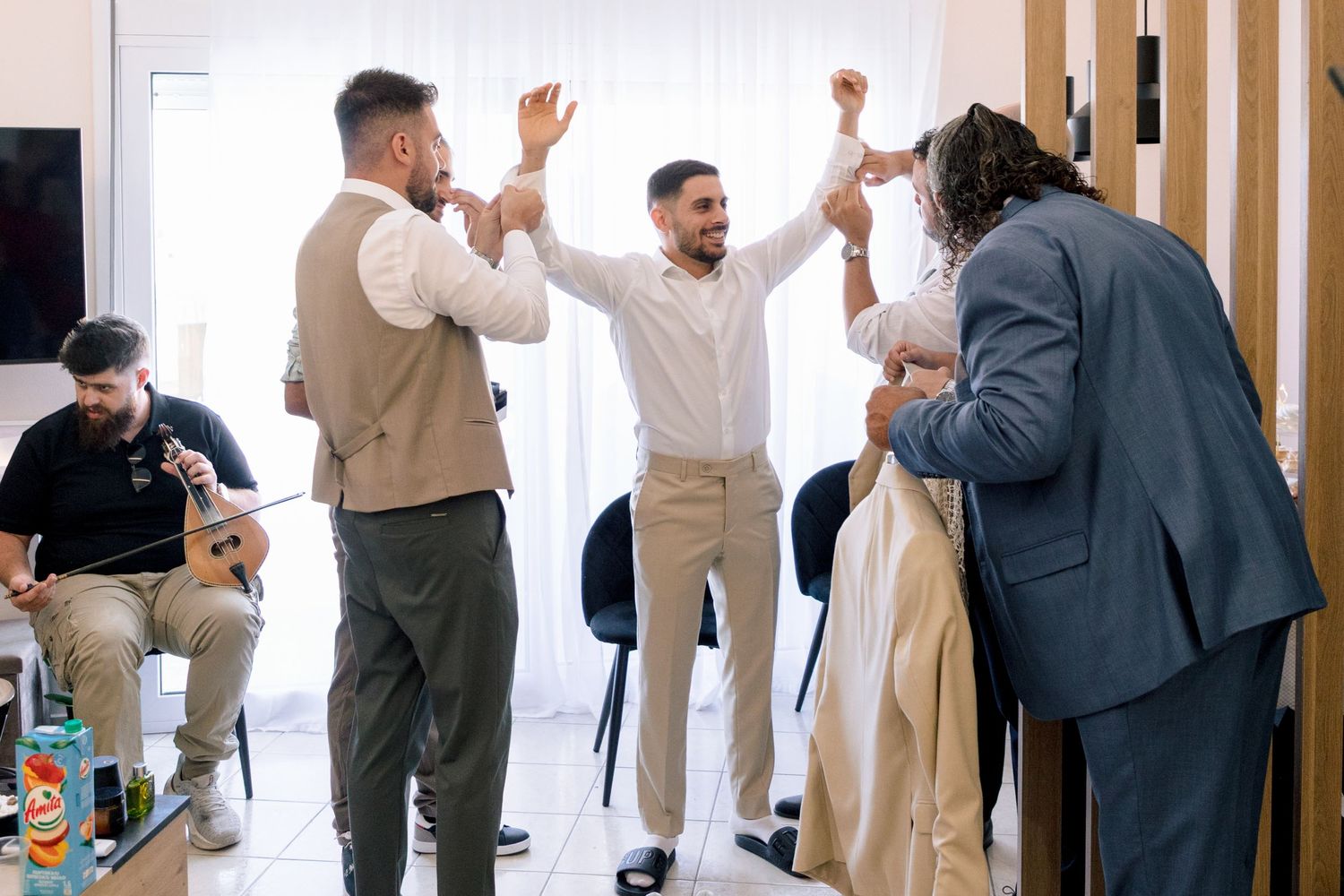Group of groomsmen interacting and celebrating in a modern indoor setting.