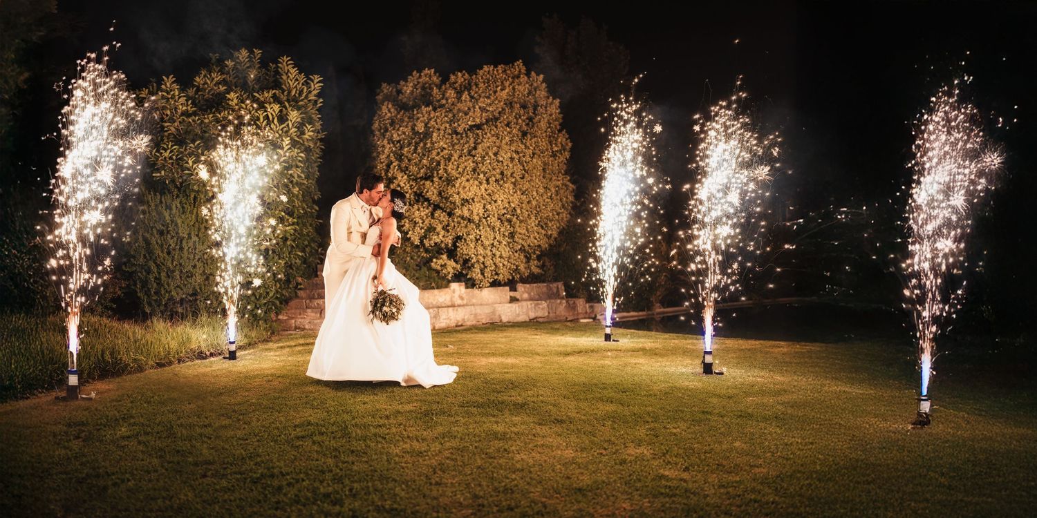 Wedding sparklers create magical light trails in an outdoor nighttime celebration.