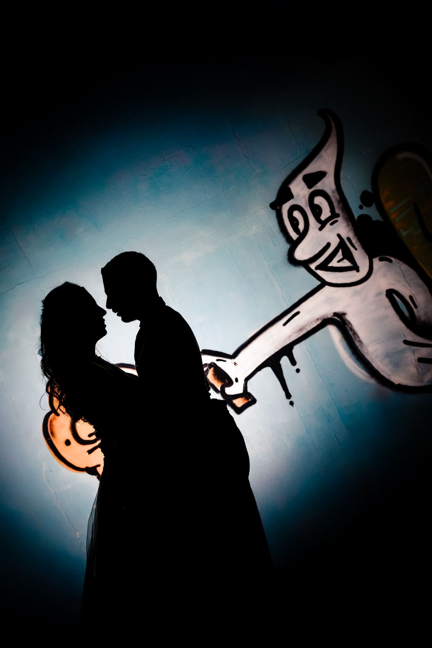 Artistic silhouettes against blue backlight create dramatic wedding photography.