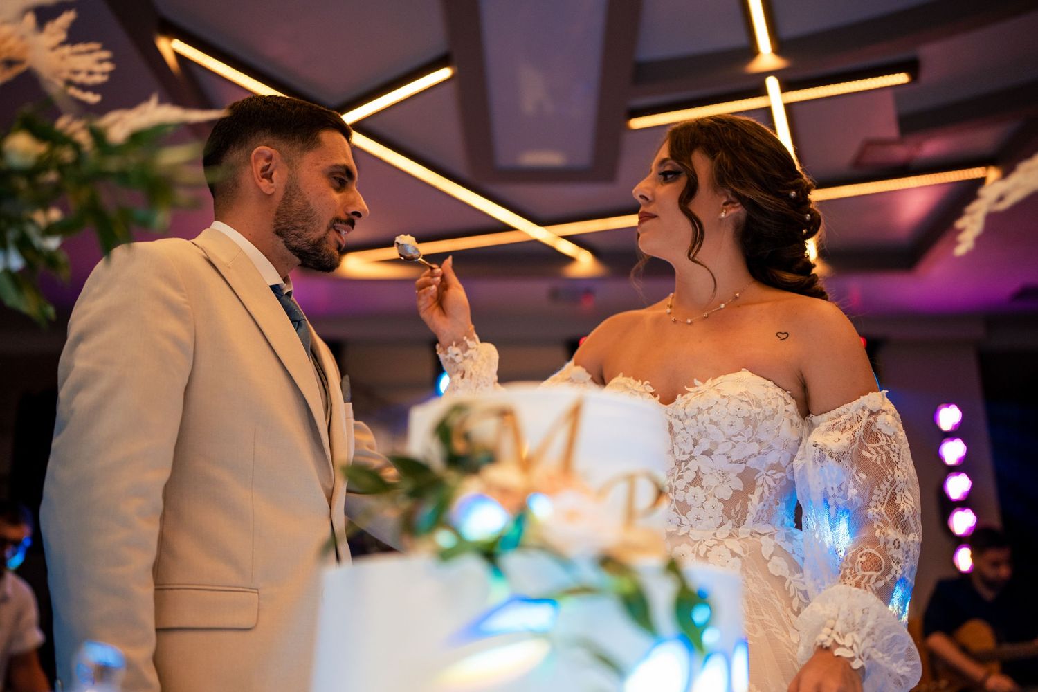 Wedding couple shares an intimate moment during their reception under ambient lighting.