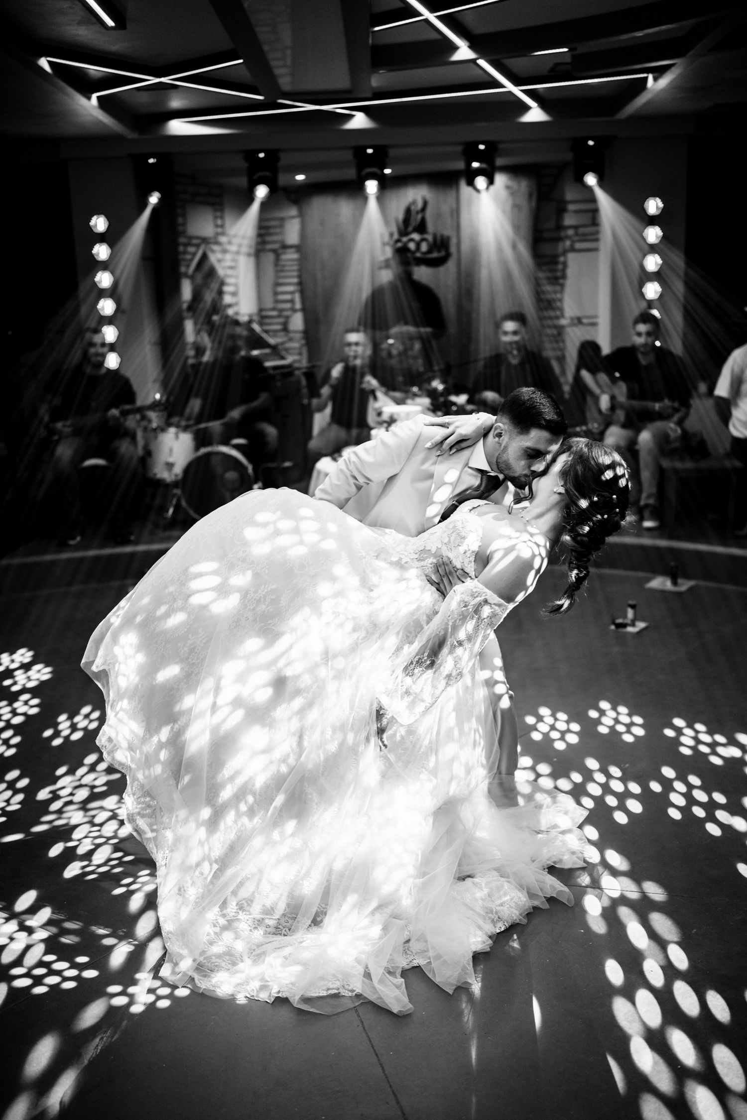 Bride in flowing white wedding dress spins on dance floor with floral light patterns projected around her.