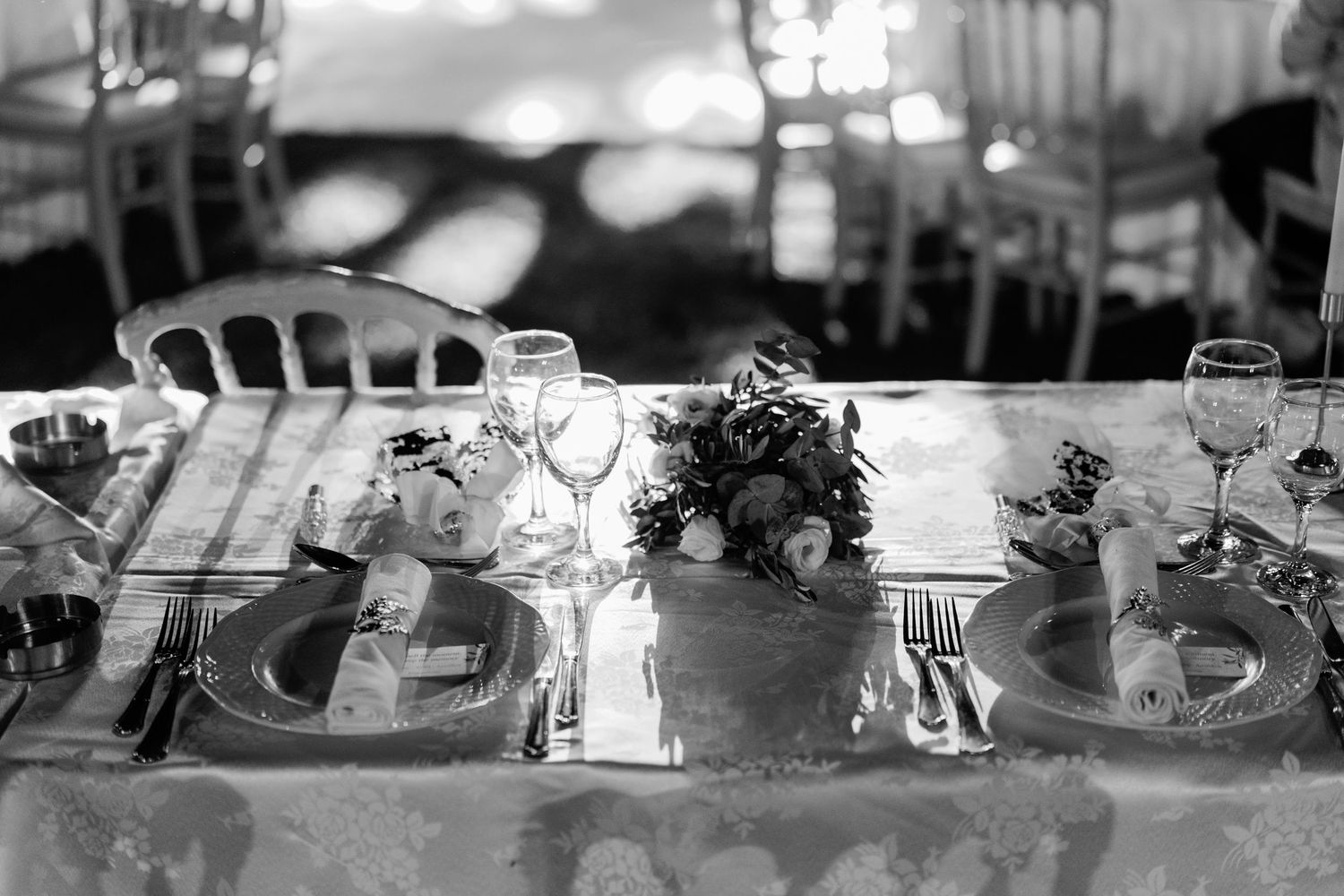 Blurred reception table settings with elegant glassware and decorative elements.
