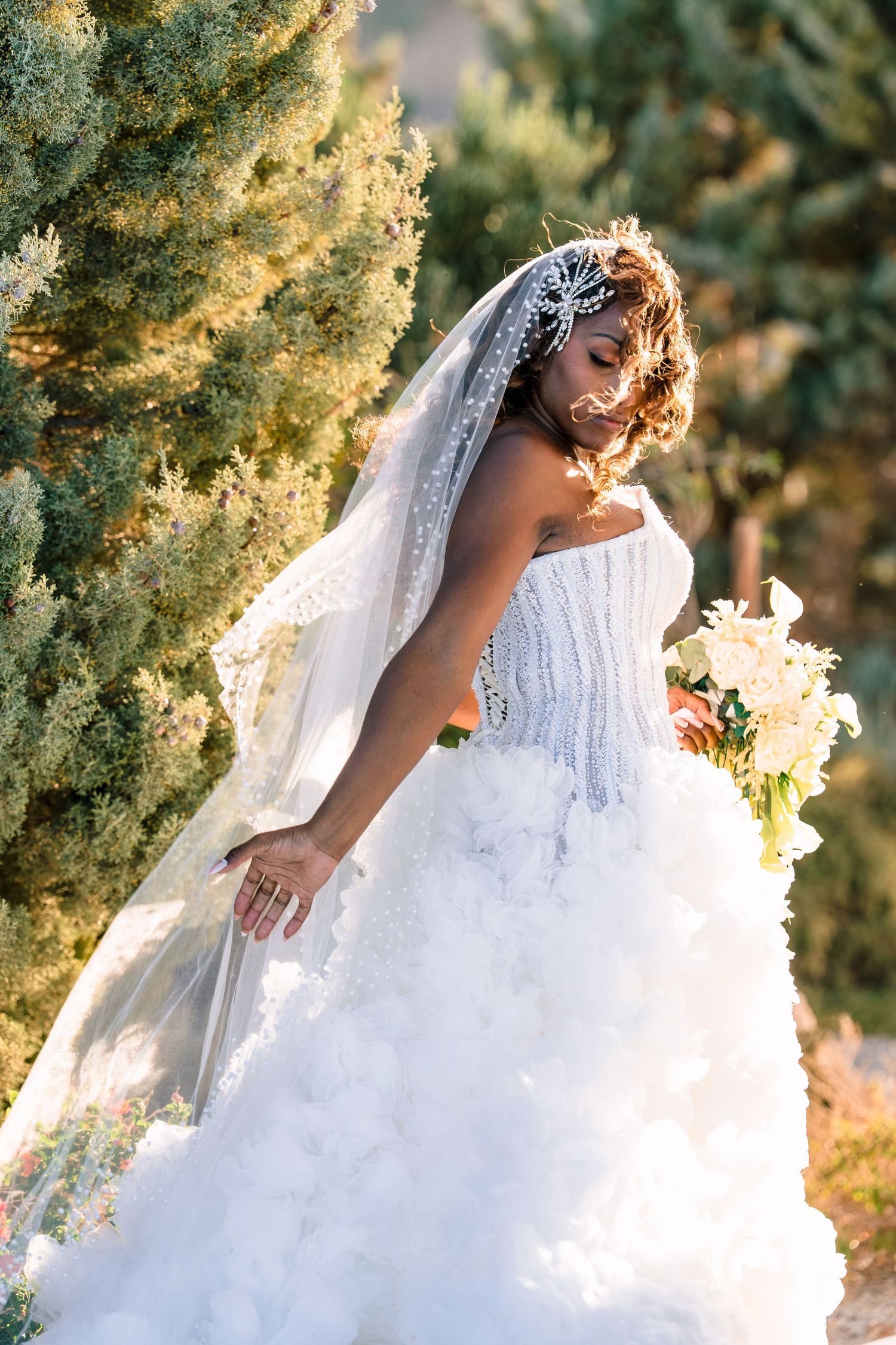 Ethereal bridal portrait with flowing white gown against golden sunset foliage.