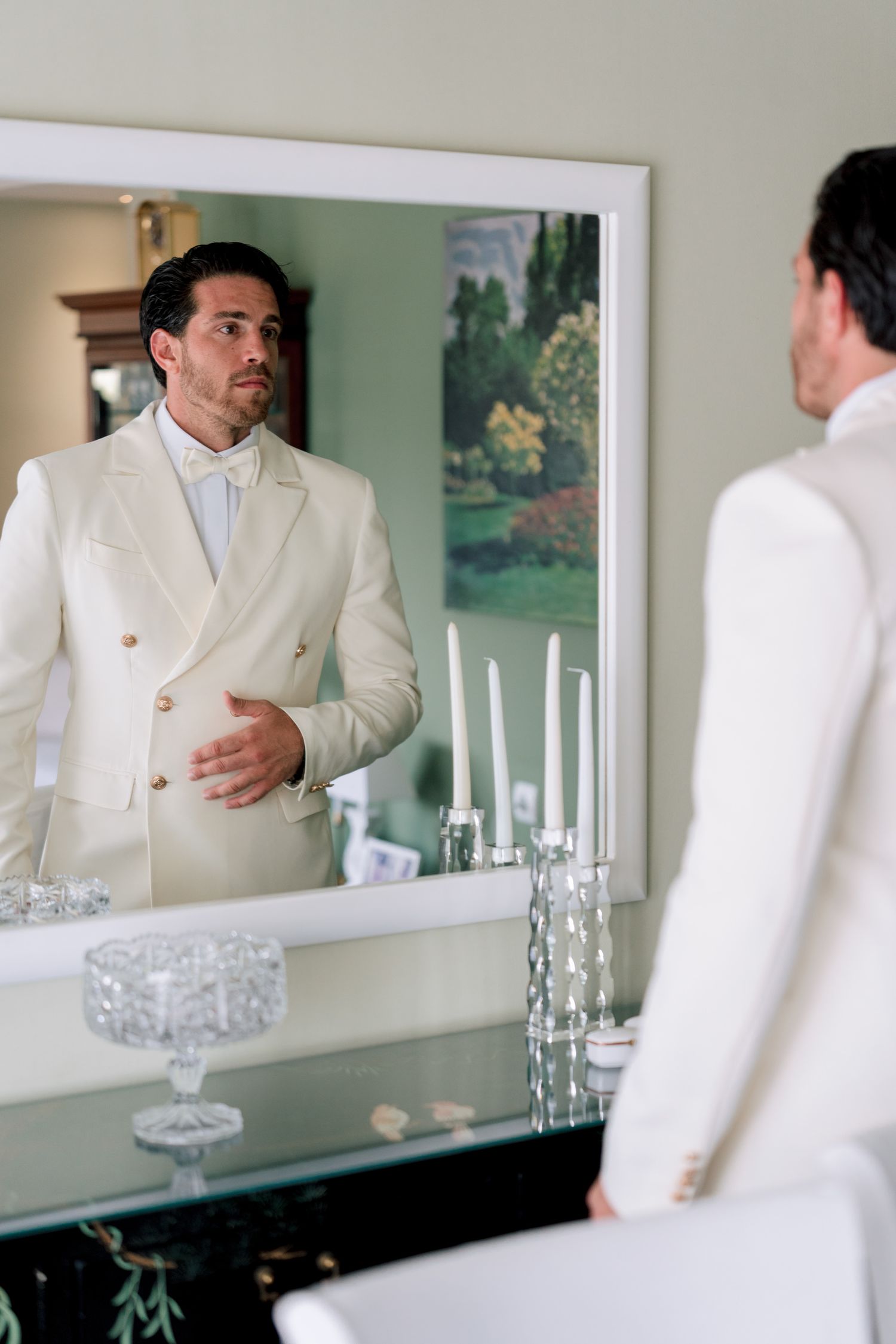 Multiple reflections in mirror showing formal white attire and elegant decor.