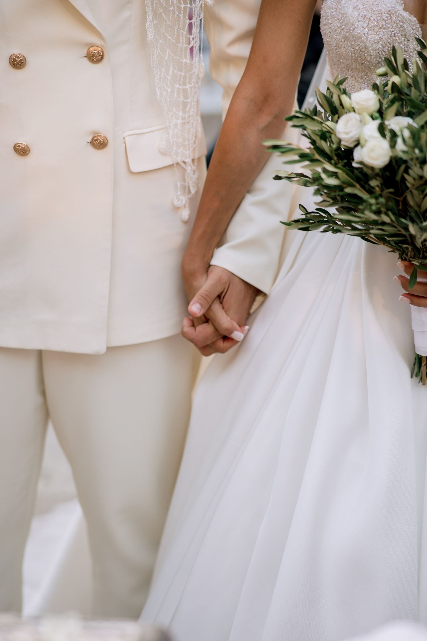 Close-up details of elegant white wedding attire with delicate lace and buttons.