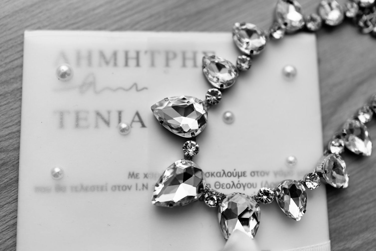 Crystal statement necklace with teardrop gems displayed on a paper invitation.