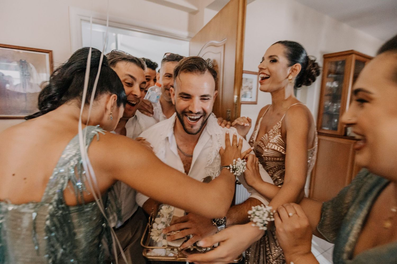Wedding party members sharing champagne and laughter during preparations.