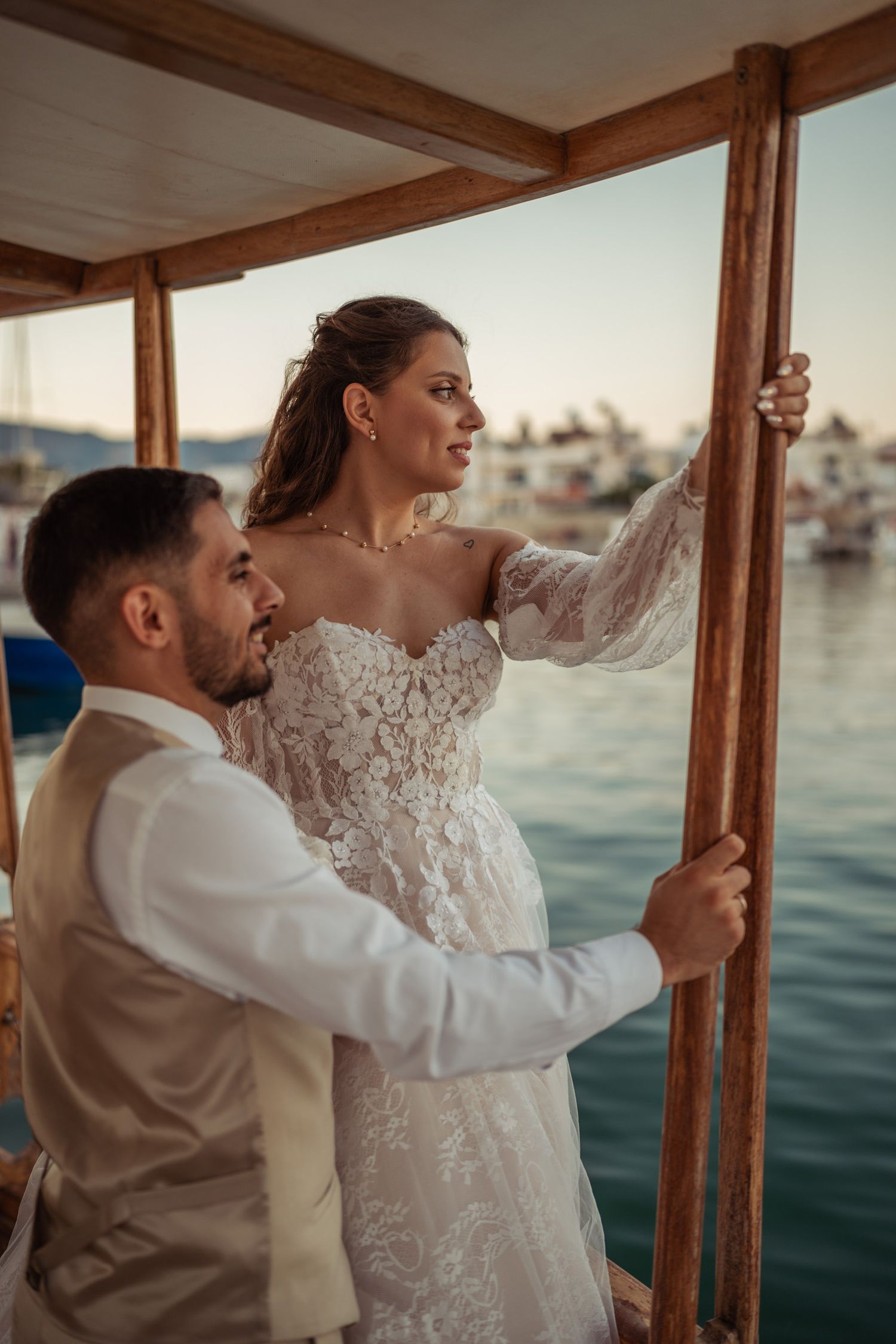 Couple in wedding attire enjoying a romantic moment on a traditional wooden boat.