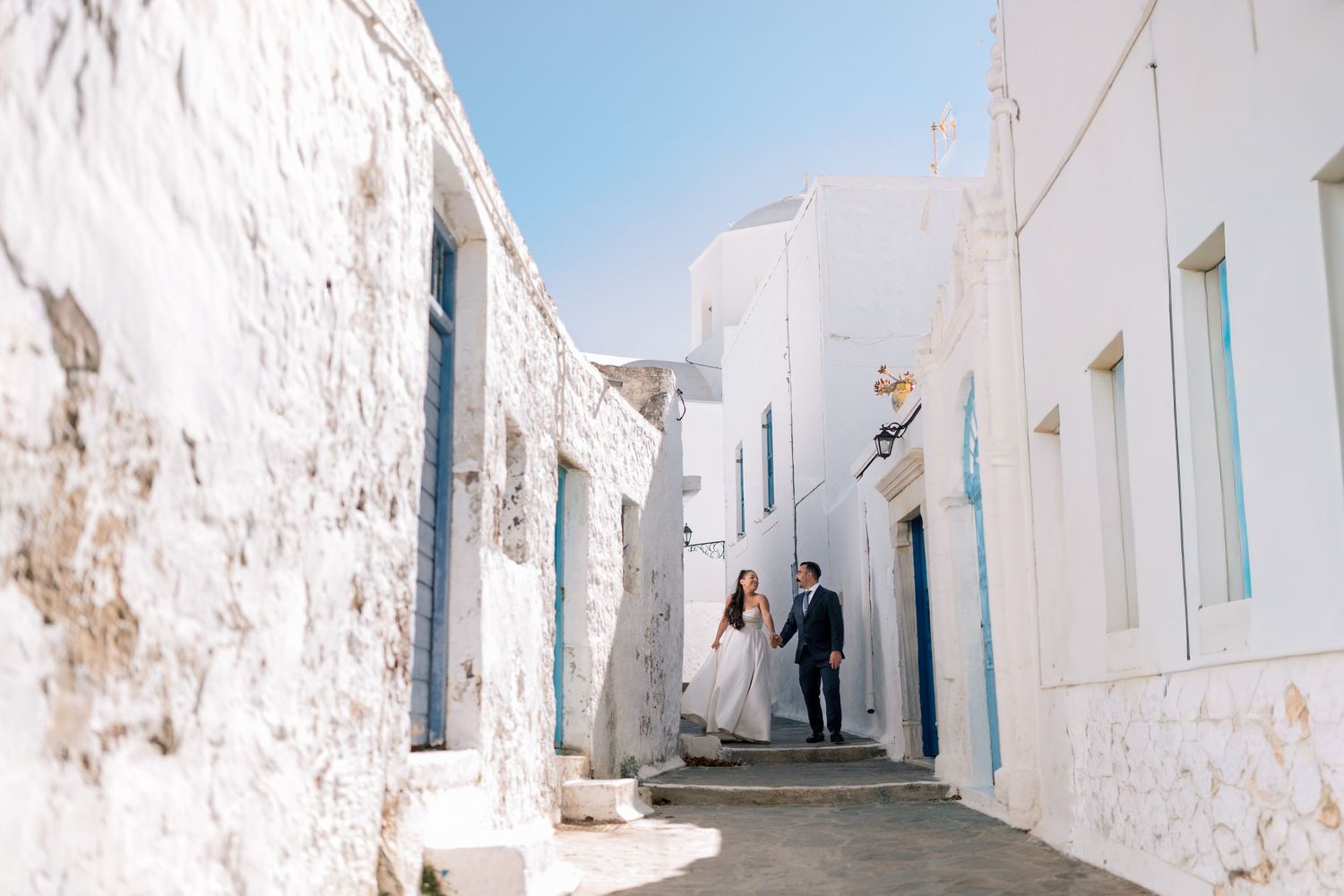 A wedding photoshoot in a picturesque white-walled Mediterranean village with blue skies.