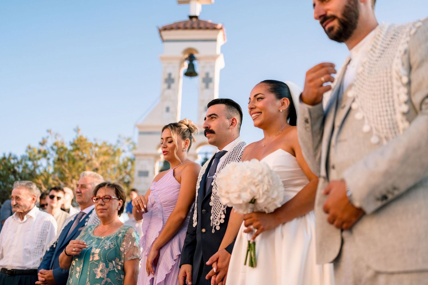 Wedding party and guests celebrating outdoors during golden hour.