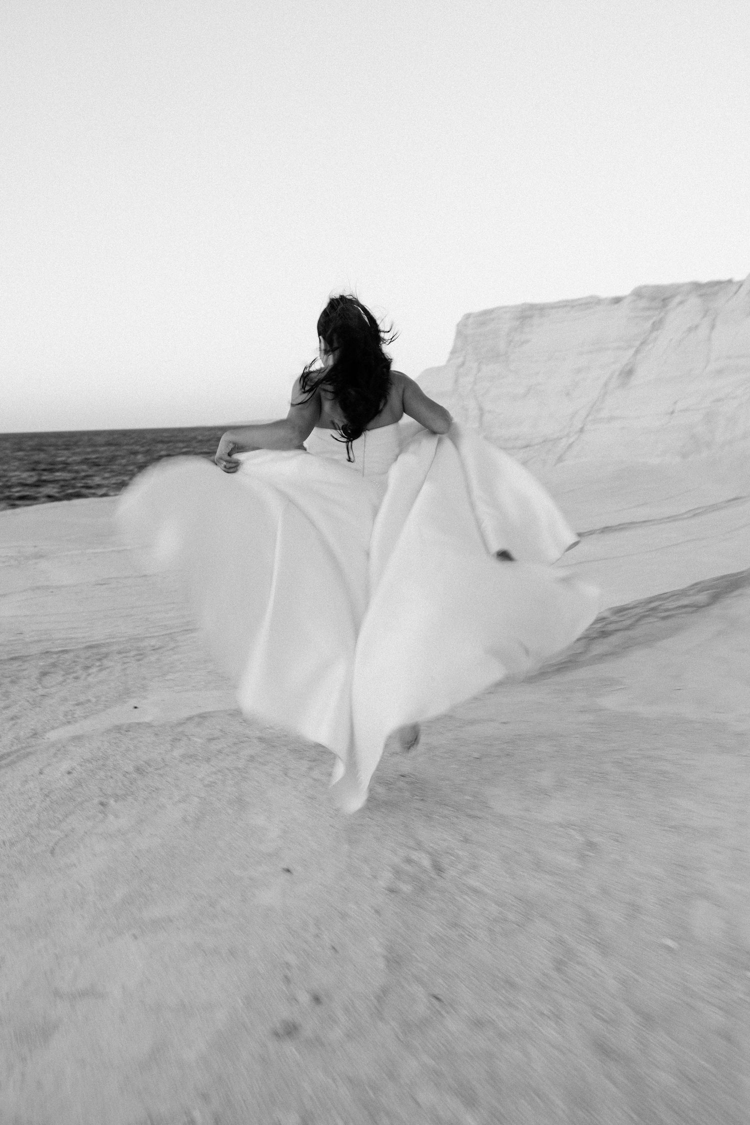 Flowing white fabric movement captured against stark white limestone formations.