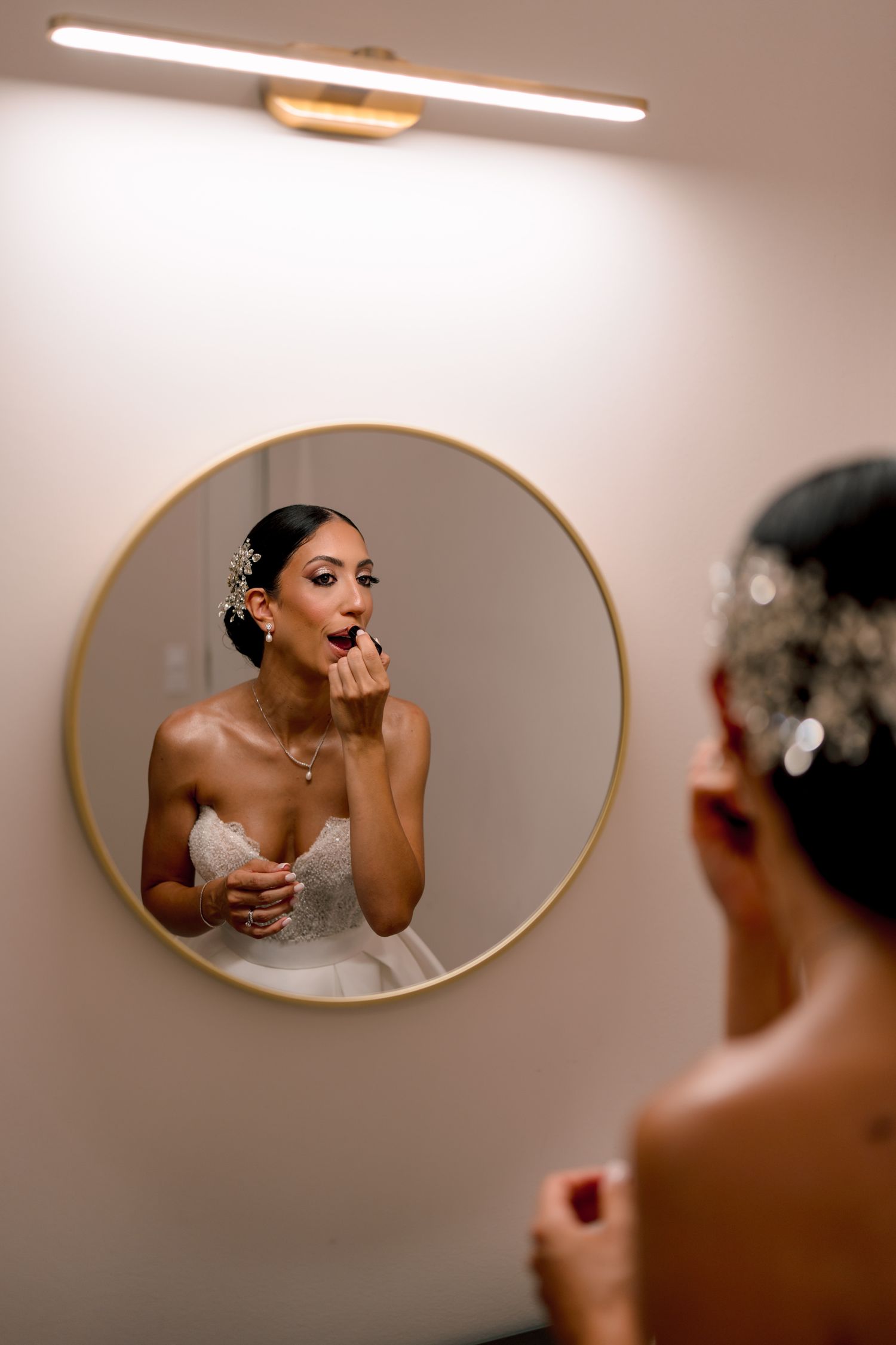 Artistic mirror reflections capture bridal preparation moments in warm lighting.