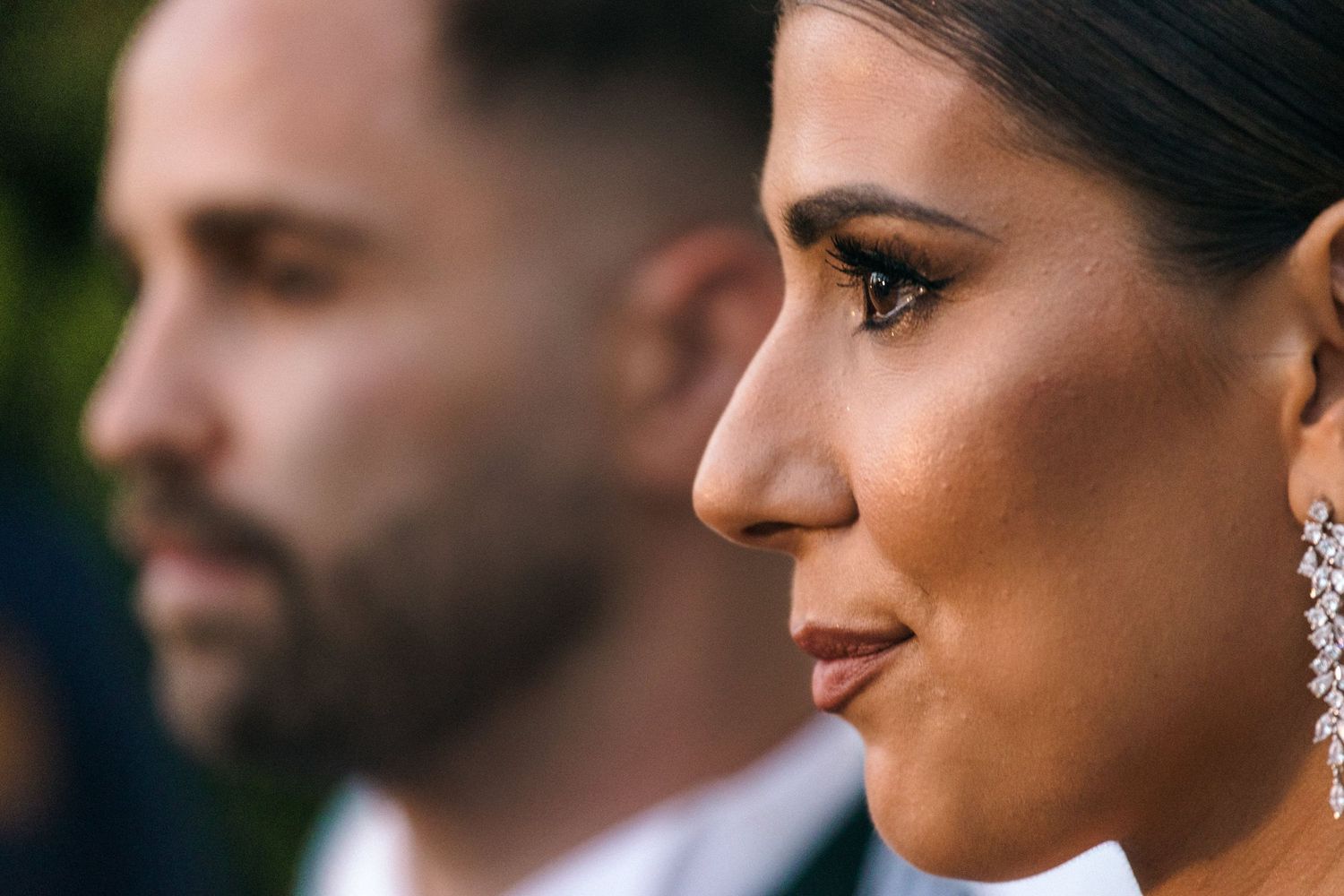 Side profile portrait in elegant wedding attire with sparkling earrings.