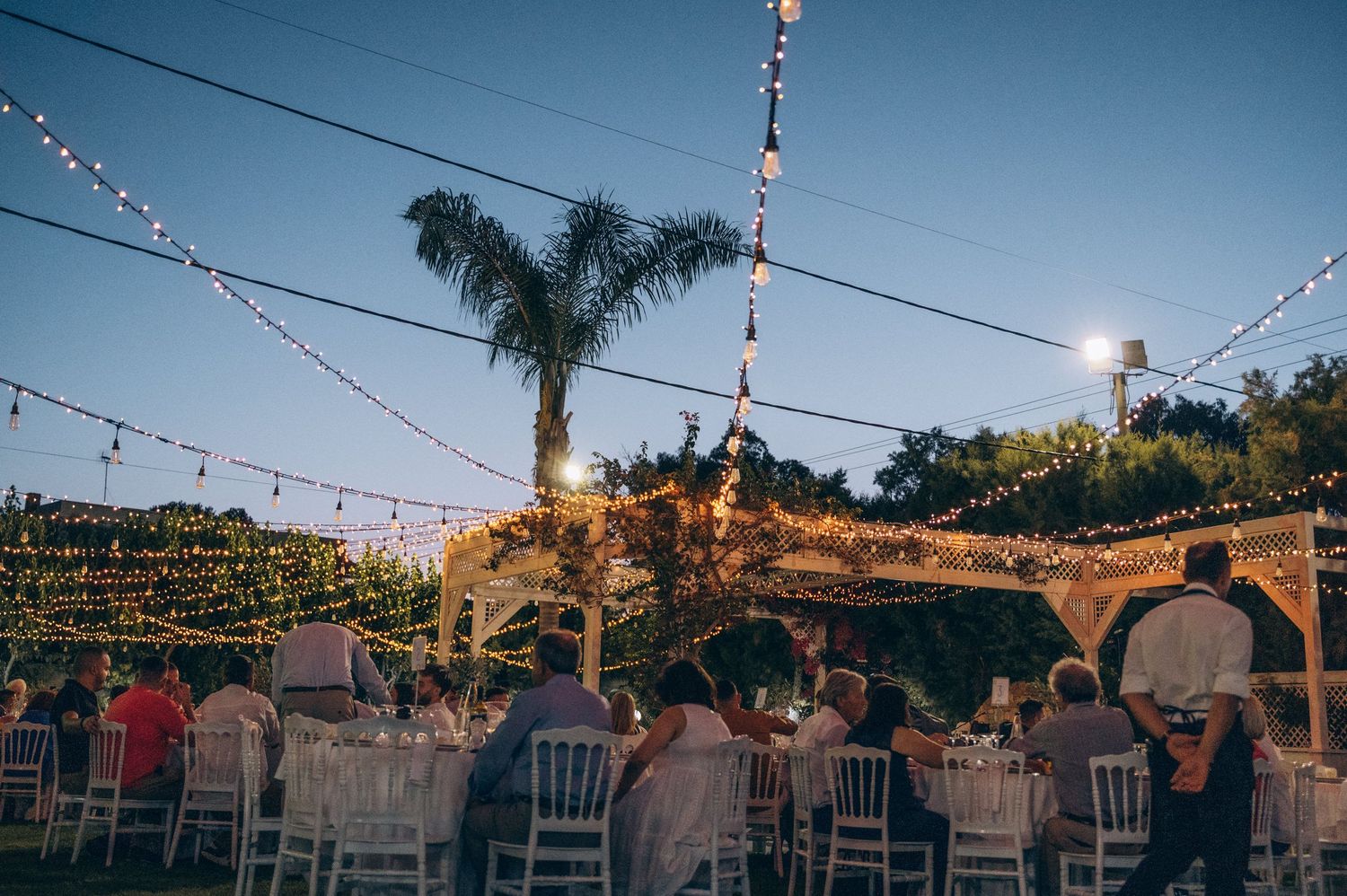 String lights hanging across an outdoor venue create a magical evening atmosphere.