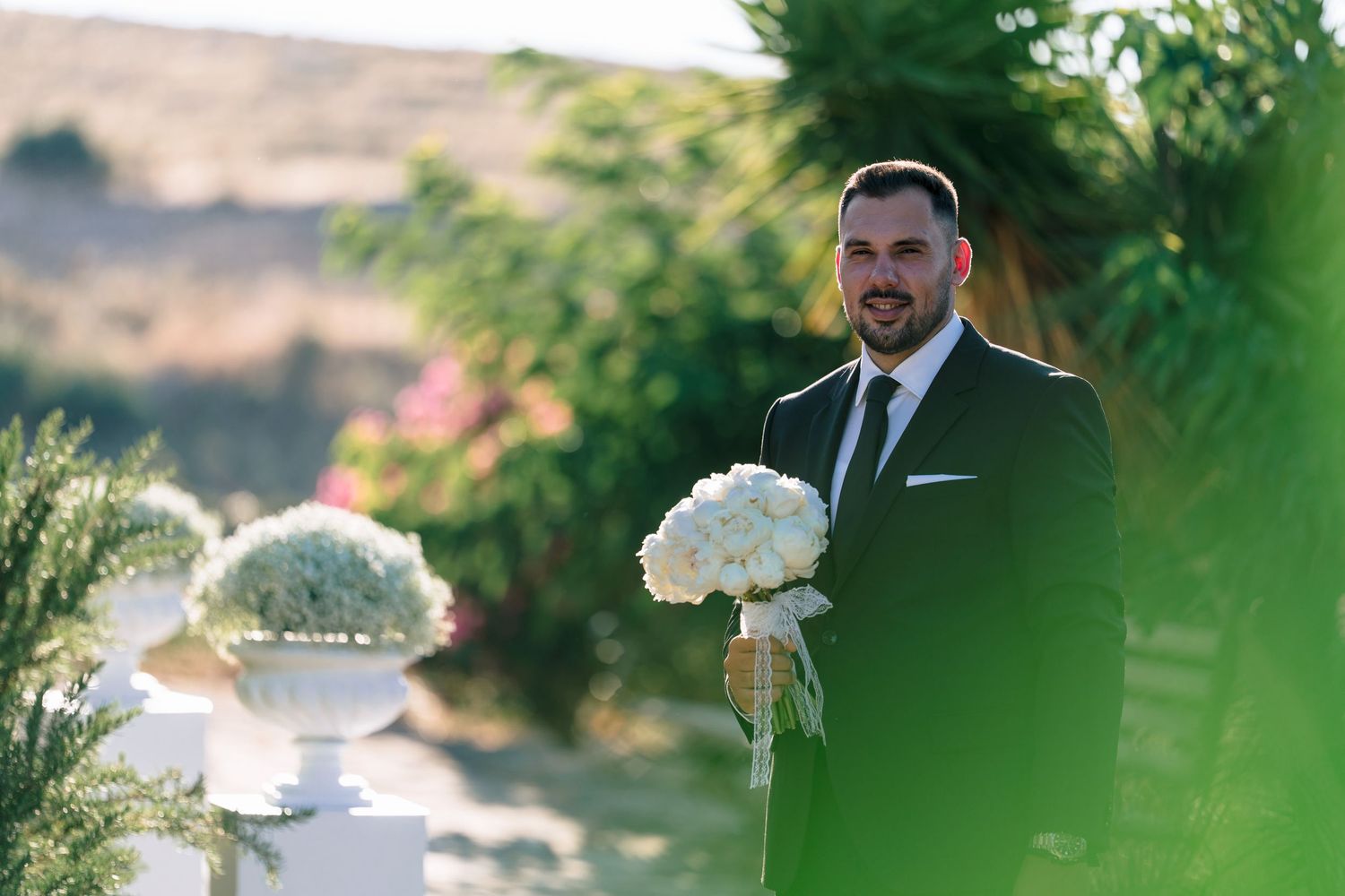 Wedding ceremony details with floral arrangements in outdoor garden setting.