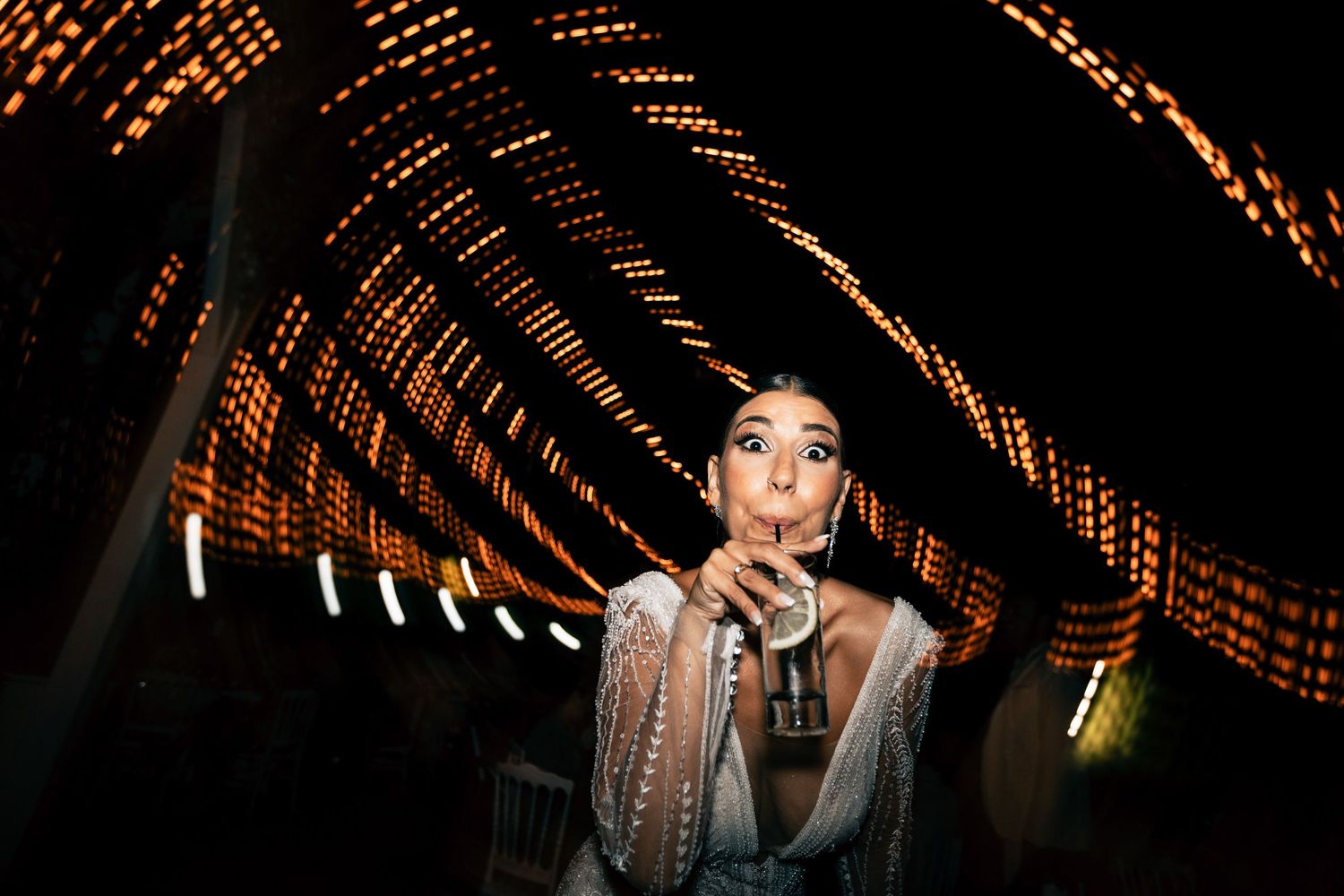 String lights create a warm geometric pattern overhead at an evening wedding reception.