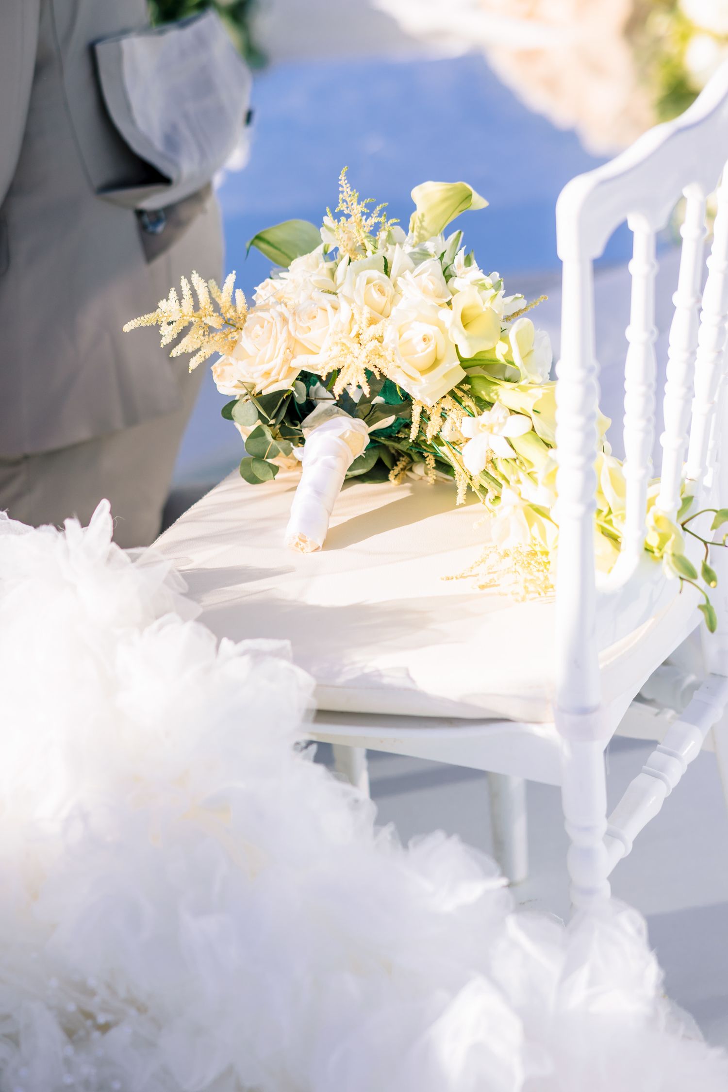 White wedding decor with floral arrangements and chiavari chairs in soft sunlight.