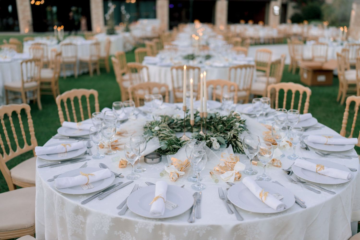 Outdoor wedding reception tables decorated with white linens and floral centerpieces.