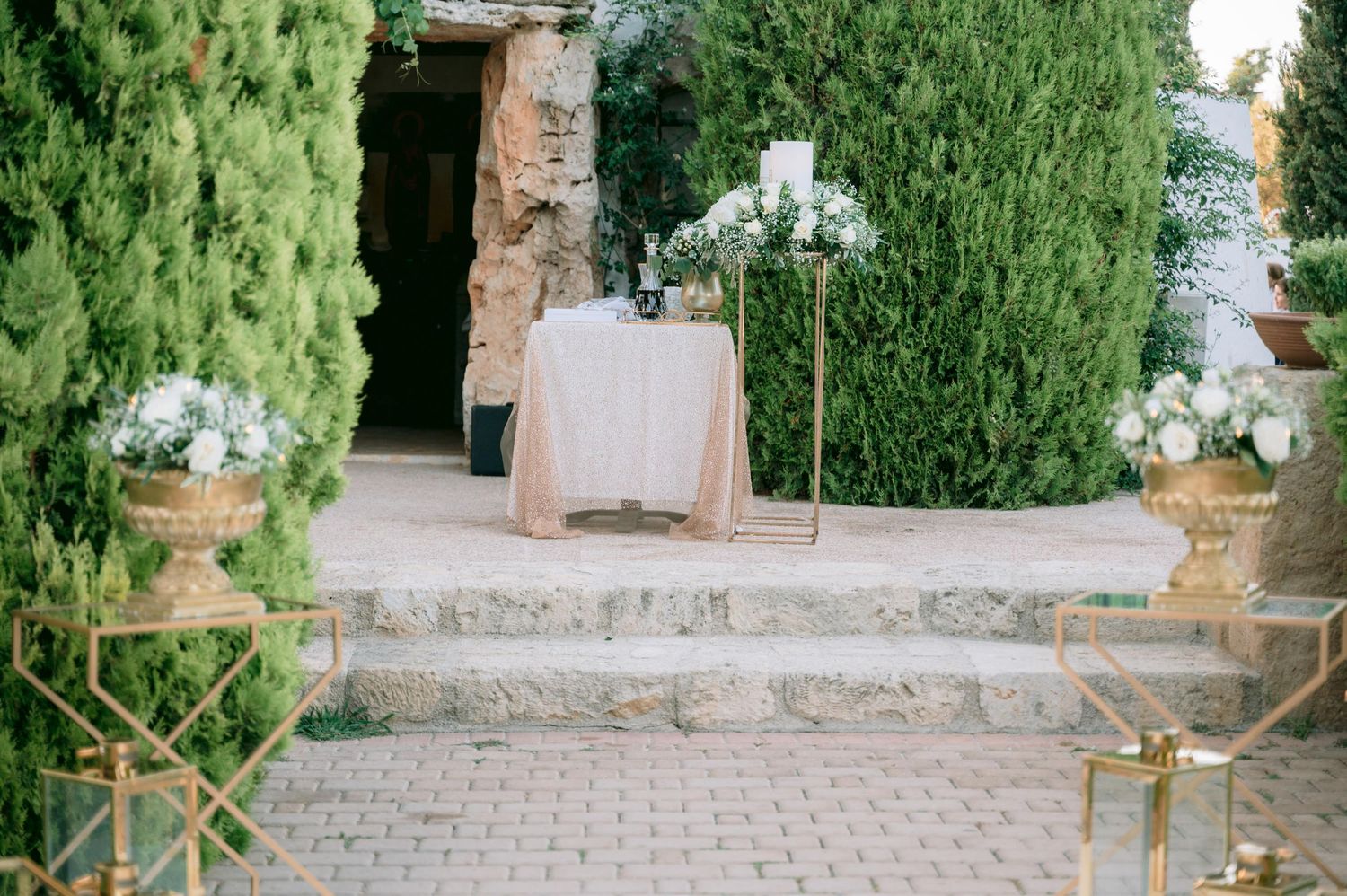 Rustic wedding ceremony setup with wooden chairs and greenery outdoors.