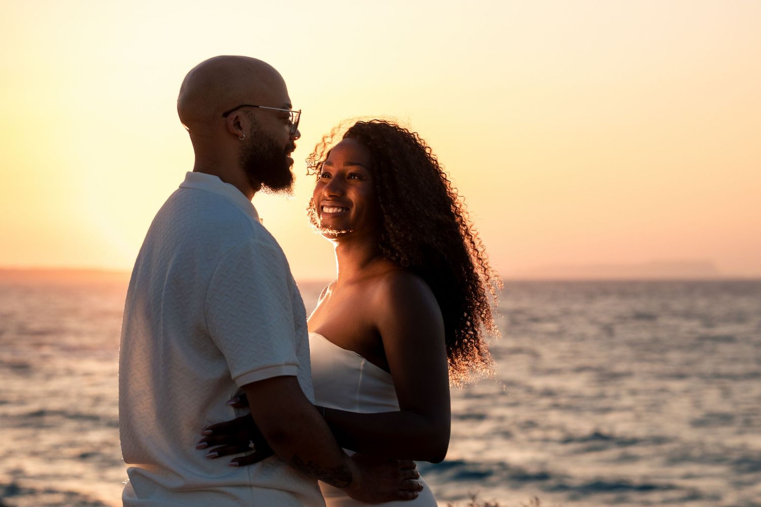 Romantic beach portraits at sunset with waves in background.