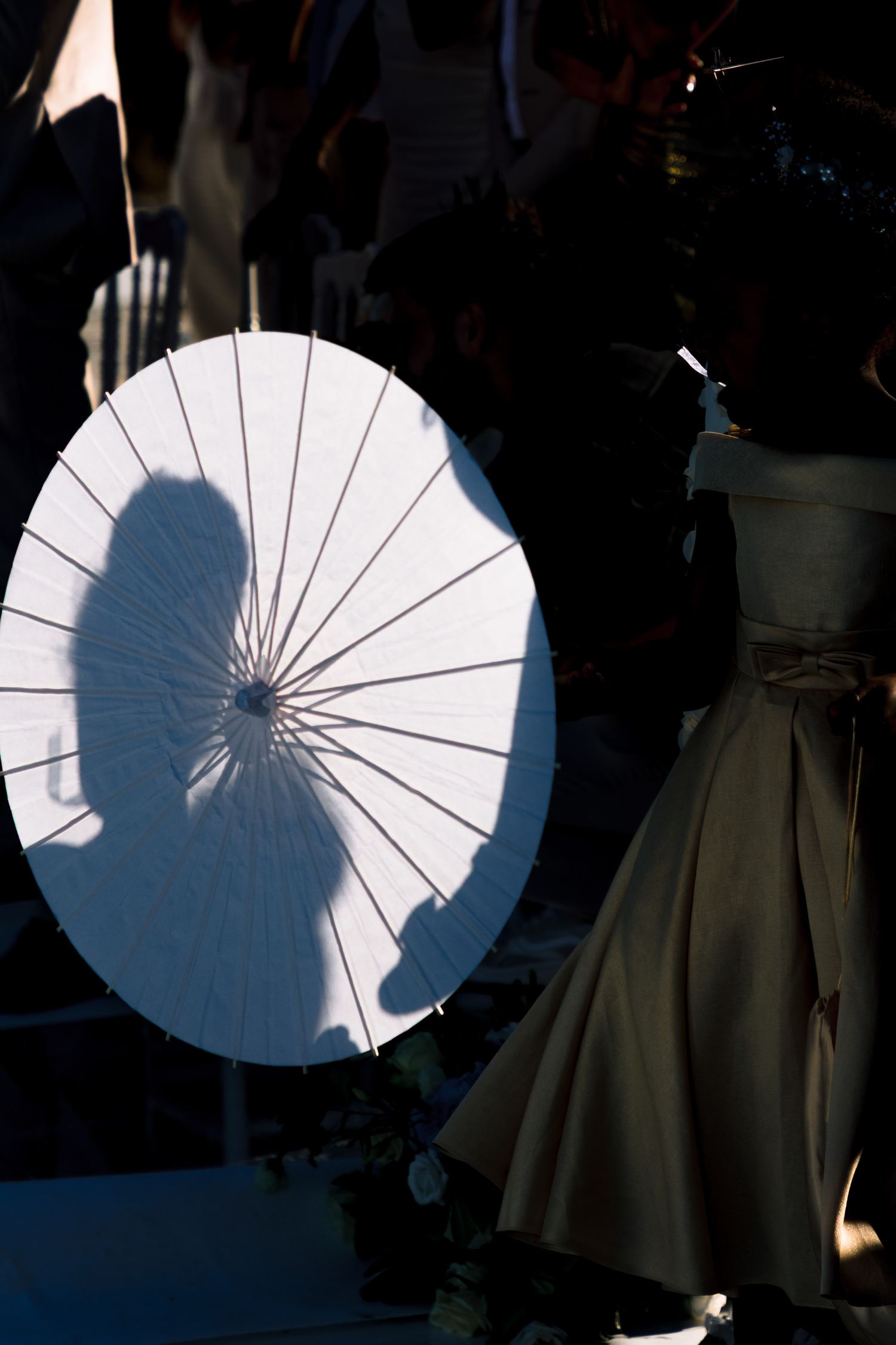 White parasols creating artistic silhouettes against a dark background at a wedding.