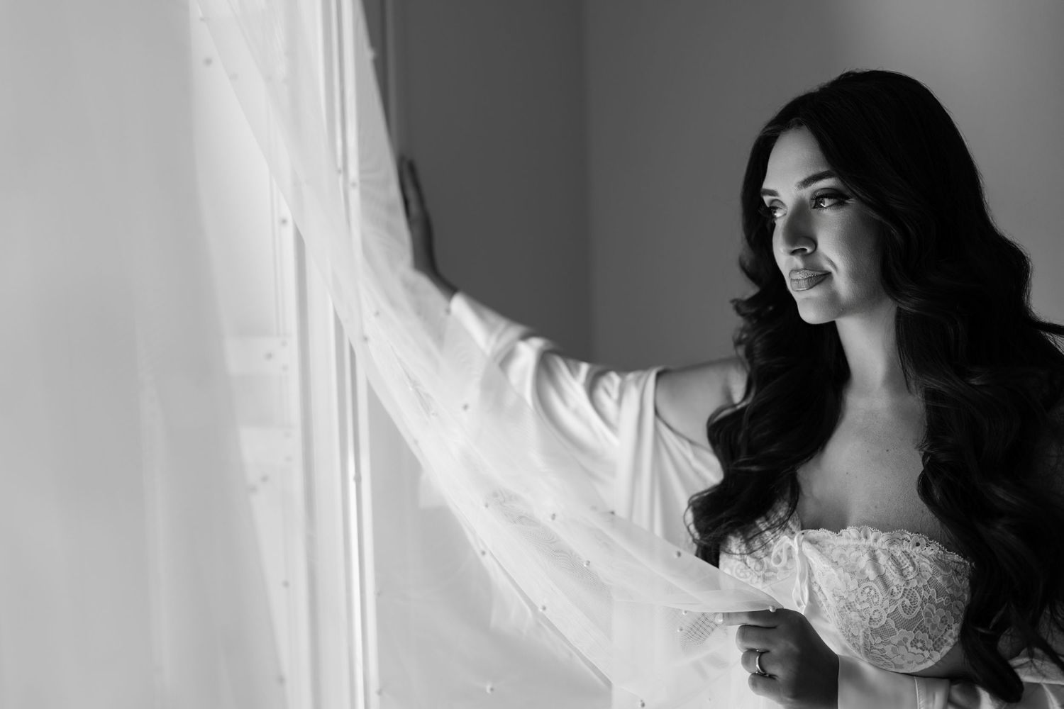 Artistic black and white bridal portrait near window with soft natural light.