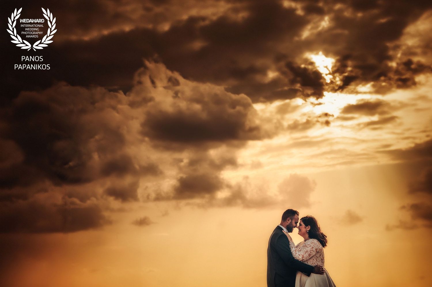 Dramatic sunset wedding photography with golden clouds and silhouettes.