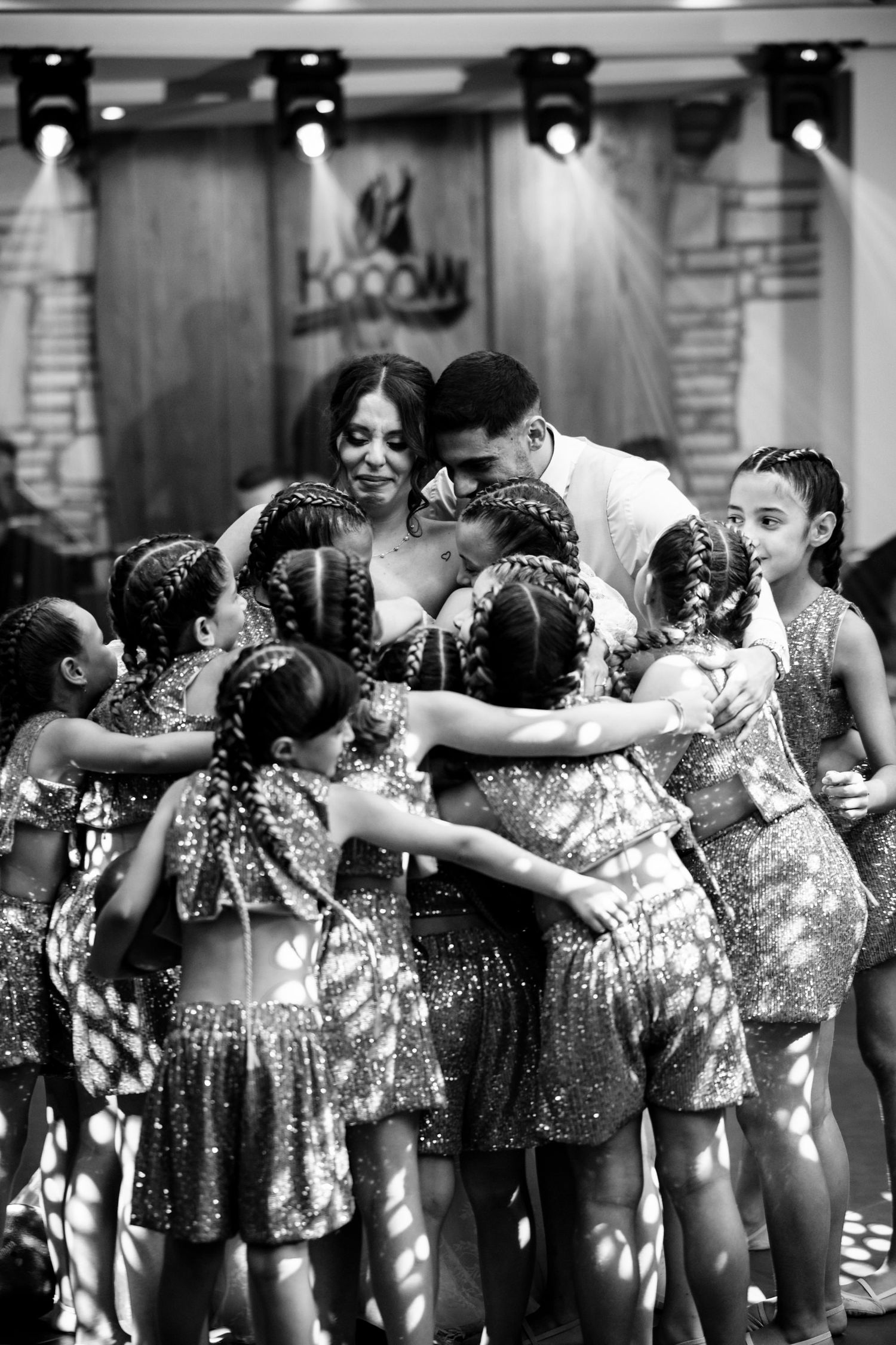 Wedding party members in sparkly dresses dance in line during reception celebration.