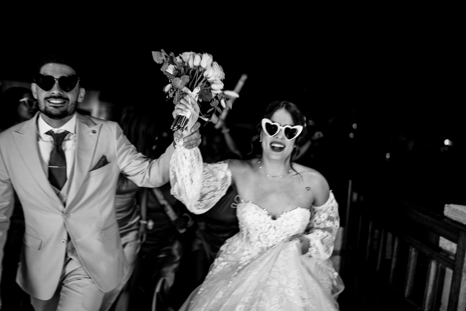 Wedding party wearing sunglasses poses together in celebration.