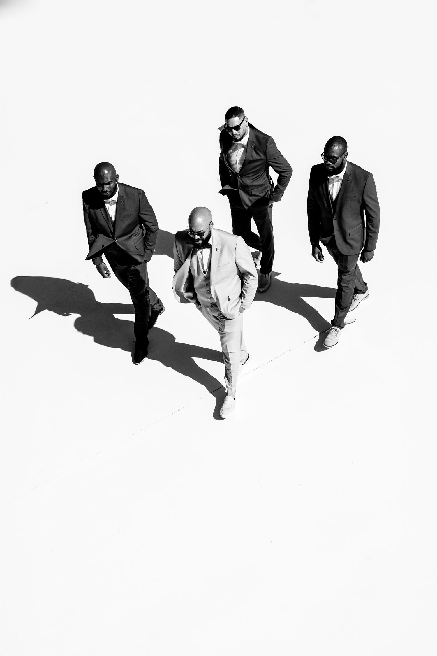 Minimalist black and white portraits of groomsmen on white background with strong shadows.