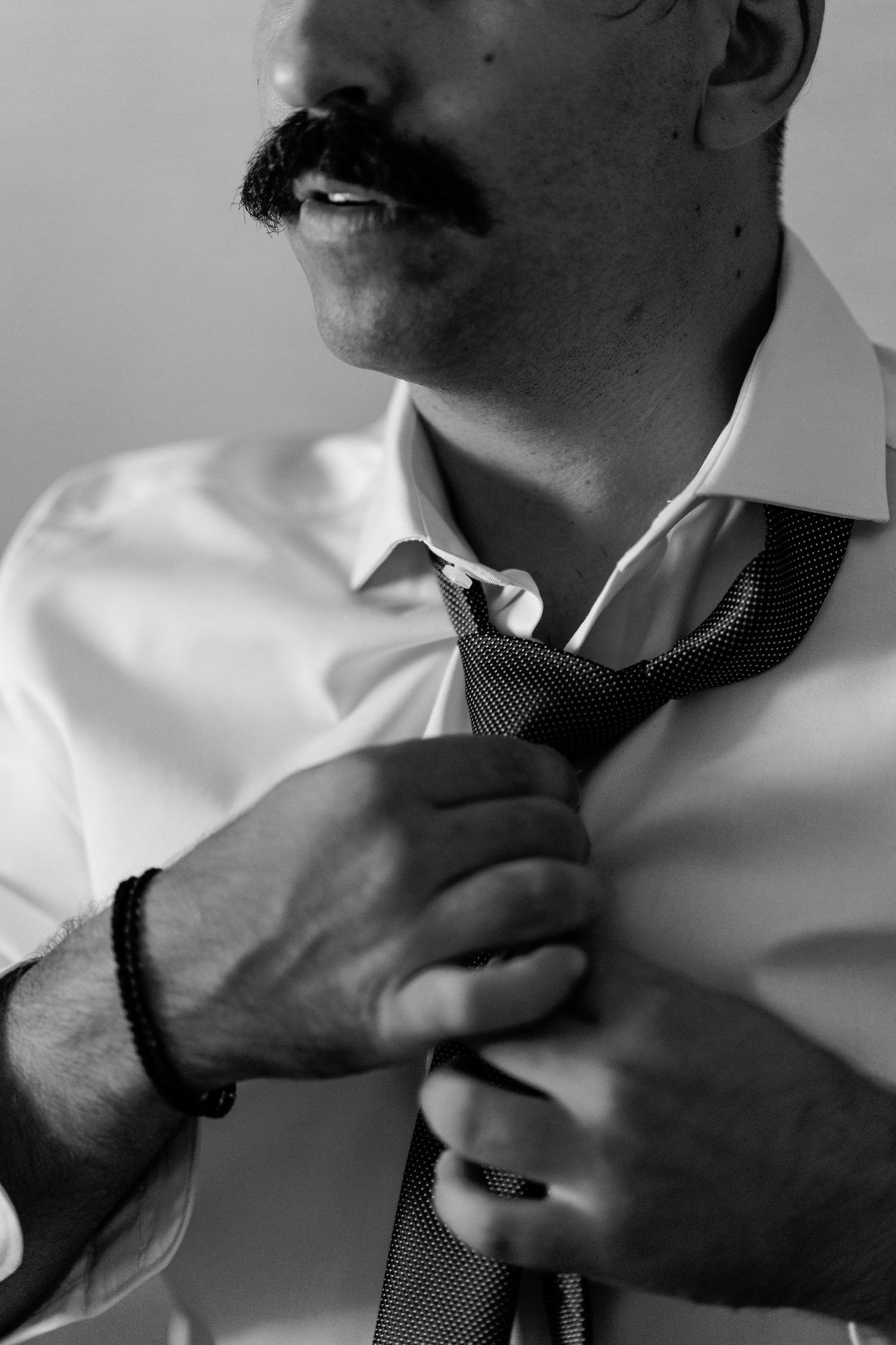 Black and white close-up of hands adjusting a necktie.