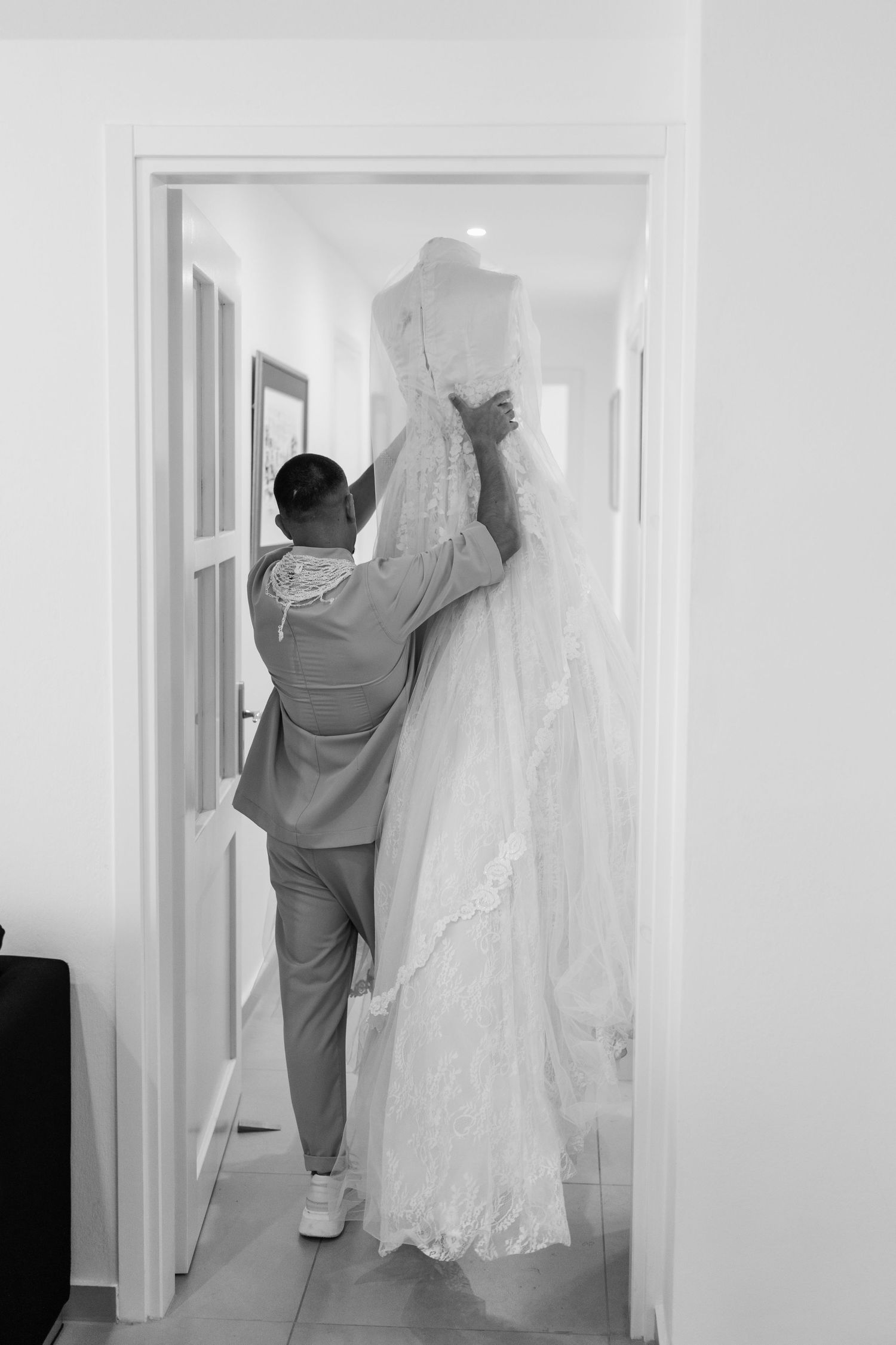 Wedding dress being carefully steamed and prepared in a hallway.