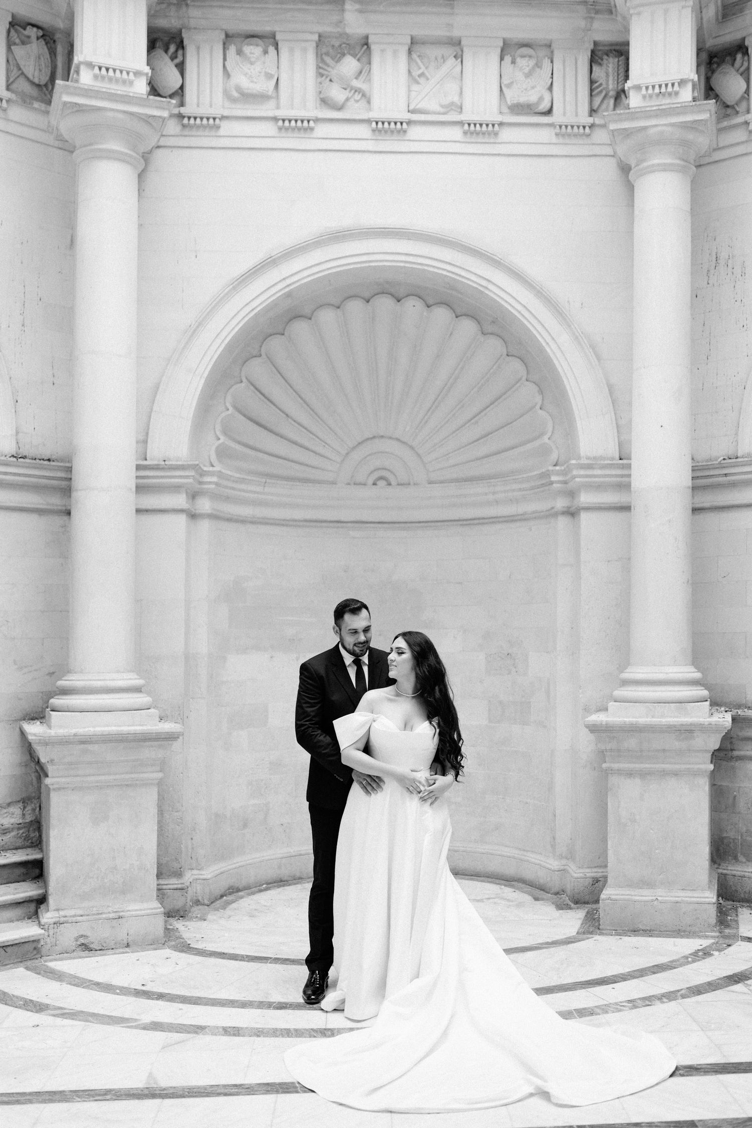 Elegant wedding photography in a grand white columned classical building interior.