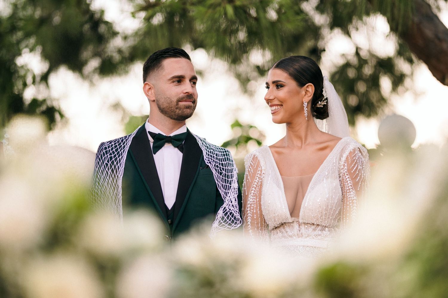 Elegant couple in formal wedding attire posing outdoors.