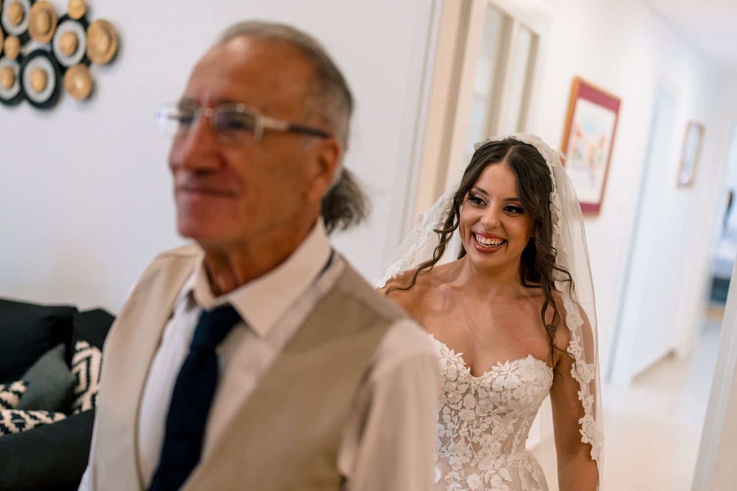 Candid moment of bride in lace gown walking down hallway.
